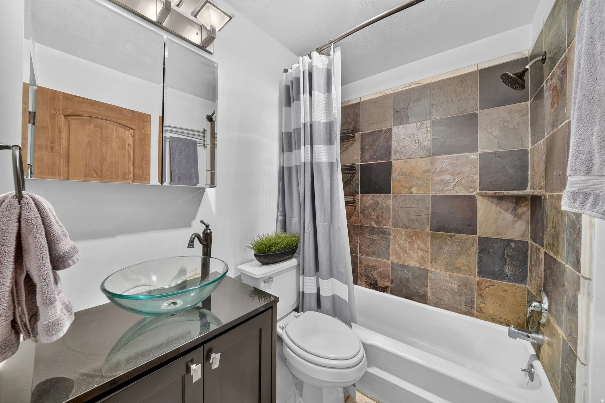 Bathroom with a slate-tiled tub and shower surround, featuring a built-in shower niche