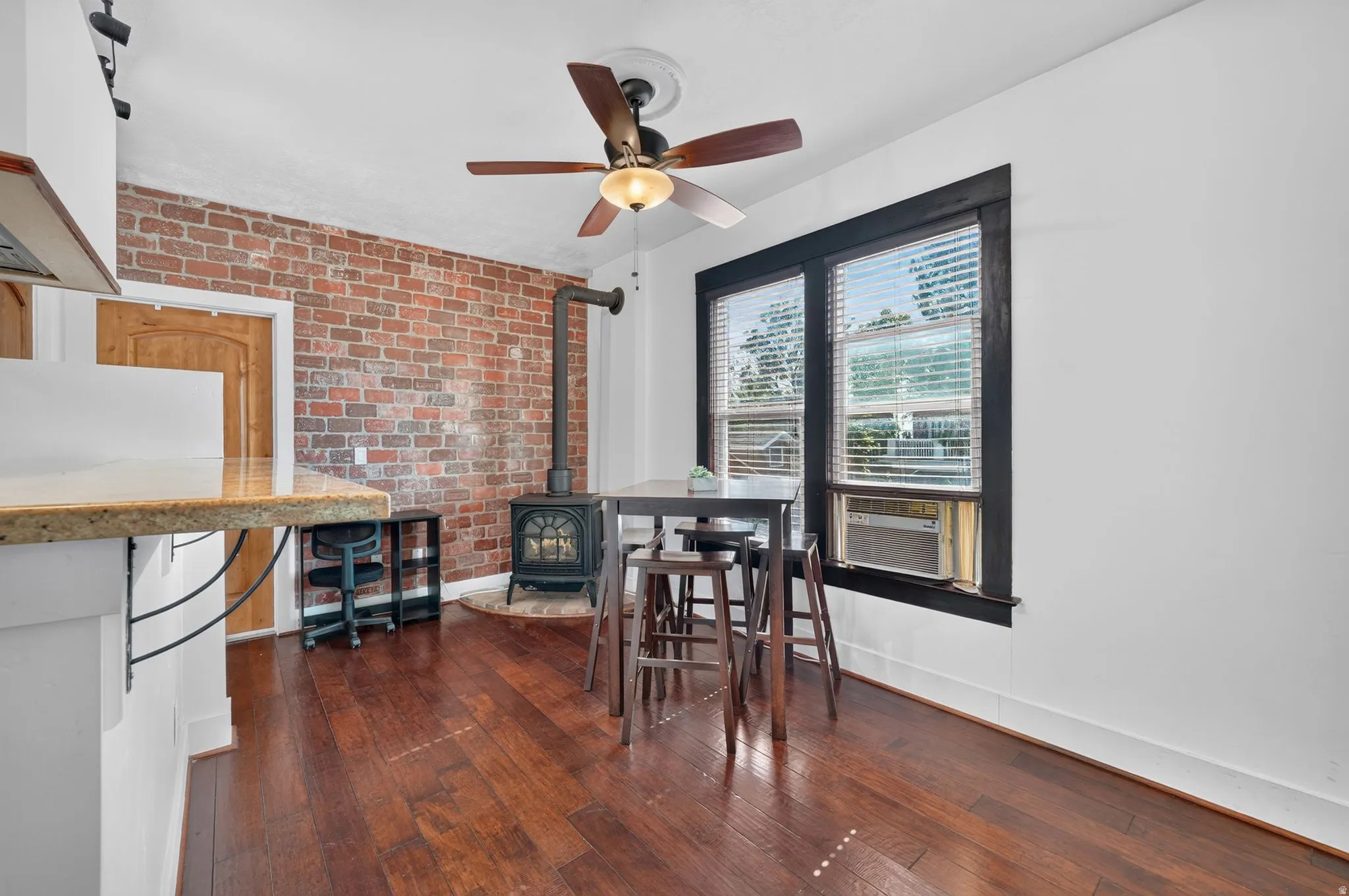 Laminate flooring throughout, complemented by a brick accent wall and a wood-burning stove