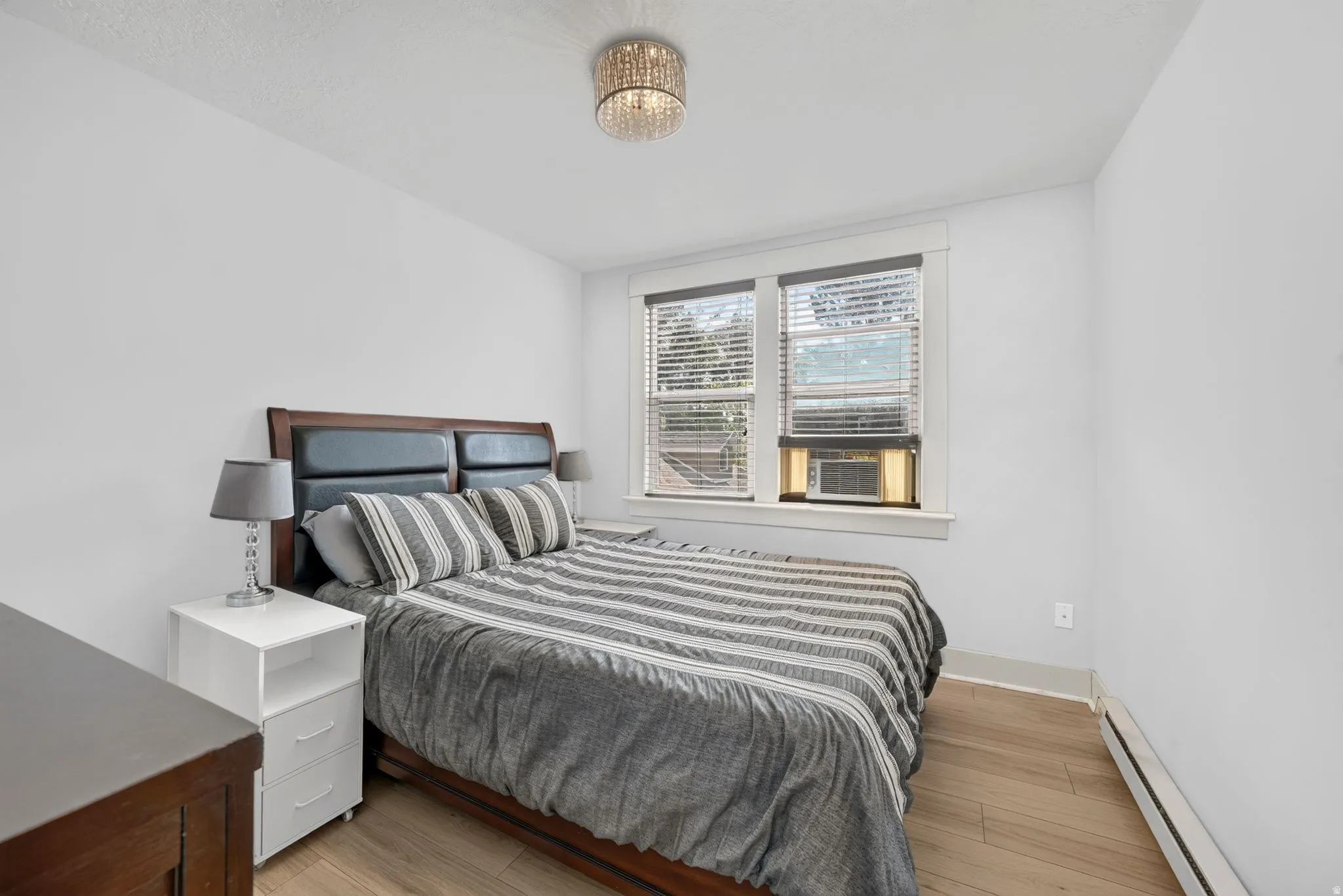 Bedroom featuring new LVP flooring, white walls, and a new crystal-adorned flush mount ceiling light