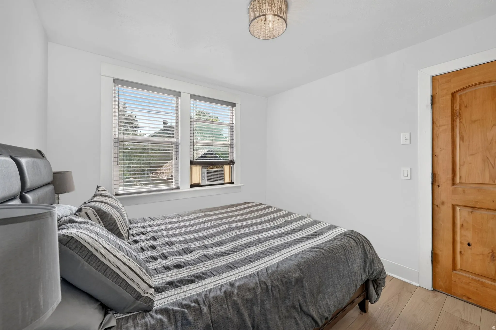 Bedroom featuring new LVP flooring, white walls, and a new crystal-adorned flush mount ceiling light