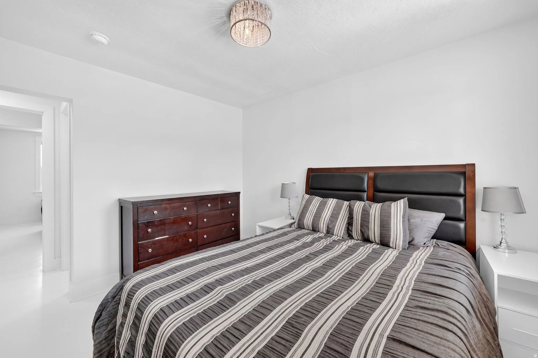 Bedroom featuring new LVP flooring, white walls, and a new crystal-adorned flush mount ceiling light