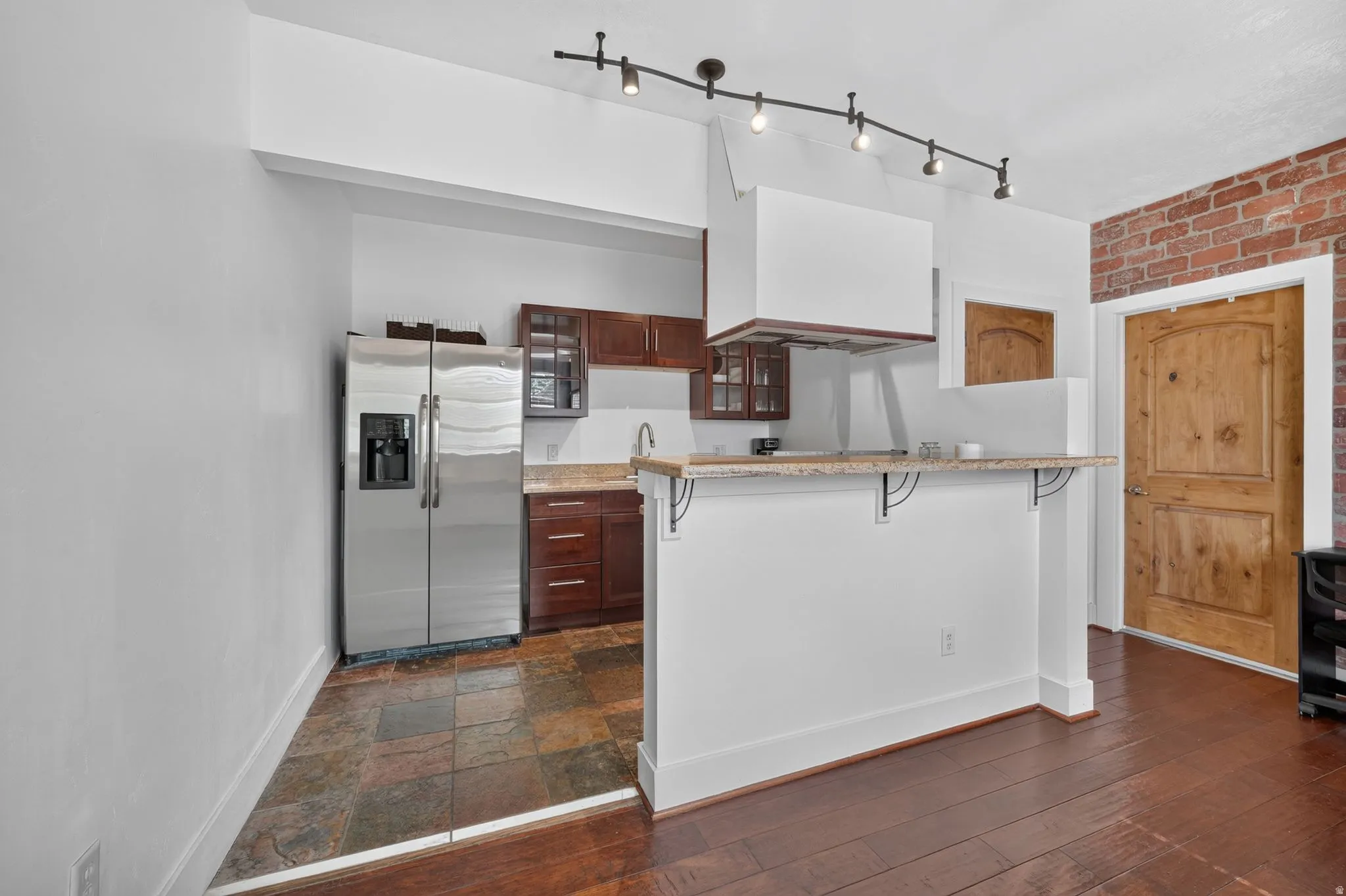 Kitchen area featuring stainless steel appliances, dark wood cabinetry, and a granite countertop