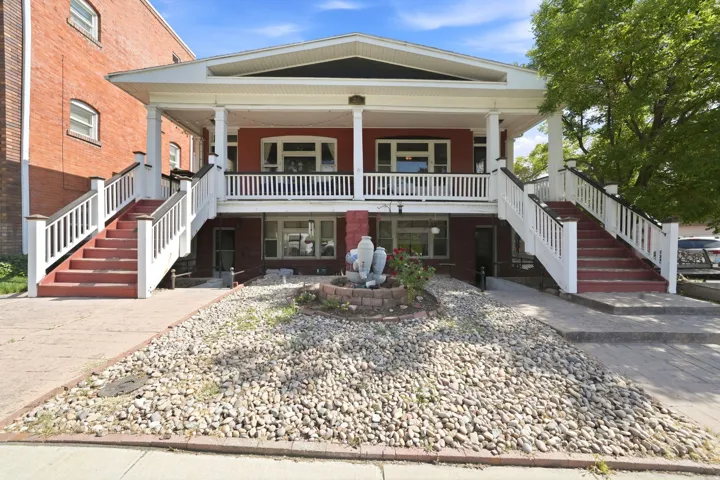 Two-story facade with a prominent upper-level porch featuring white railings and columns