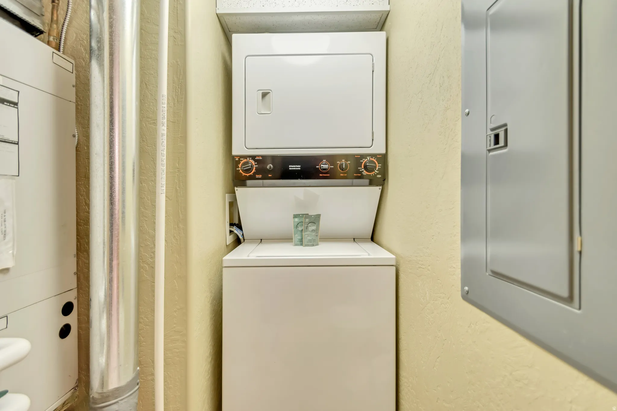 Dedicated laundry area with a stackable washer and dryer unit, featuring white appliance finishes and a top-loading washer