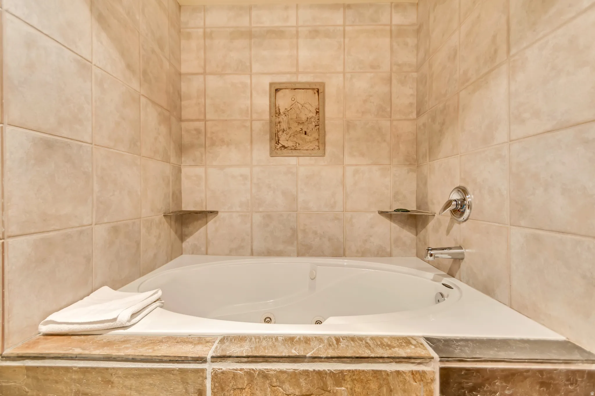 White jetted soaking tub with a tiled surround