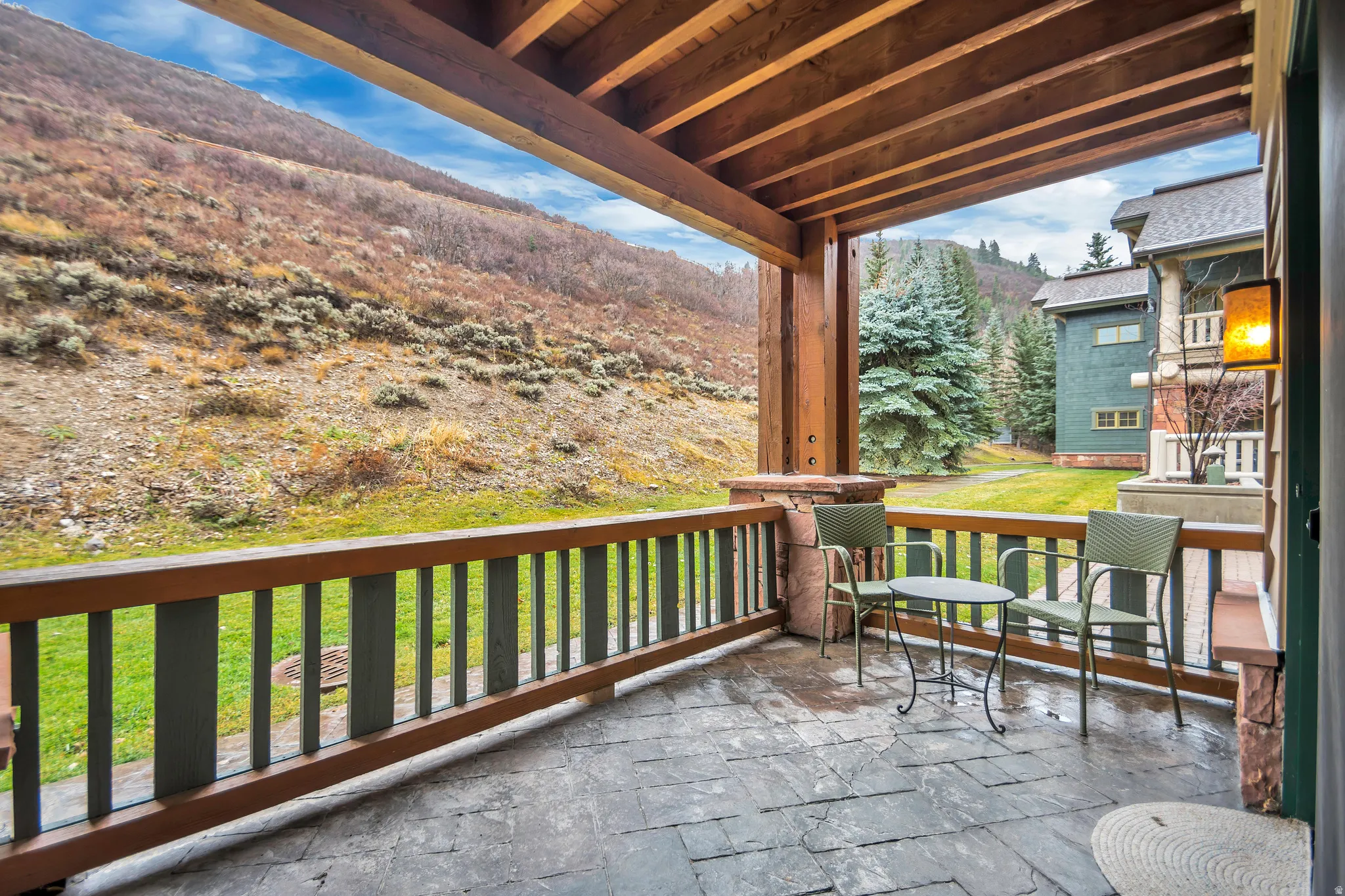 Covered outdoor patio with a stamped concrete floor, rough-hewn timber posts, and a wood railing