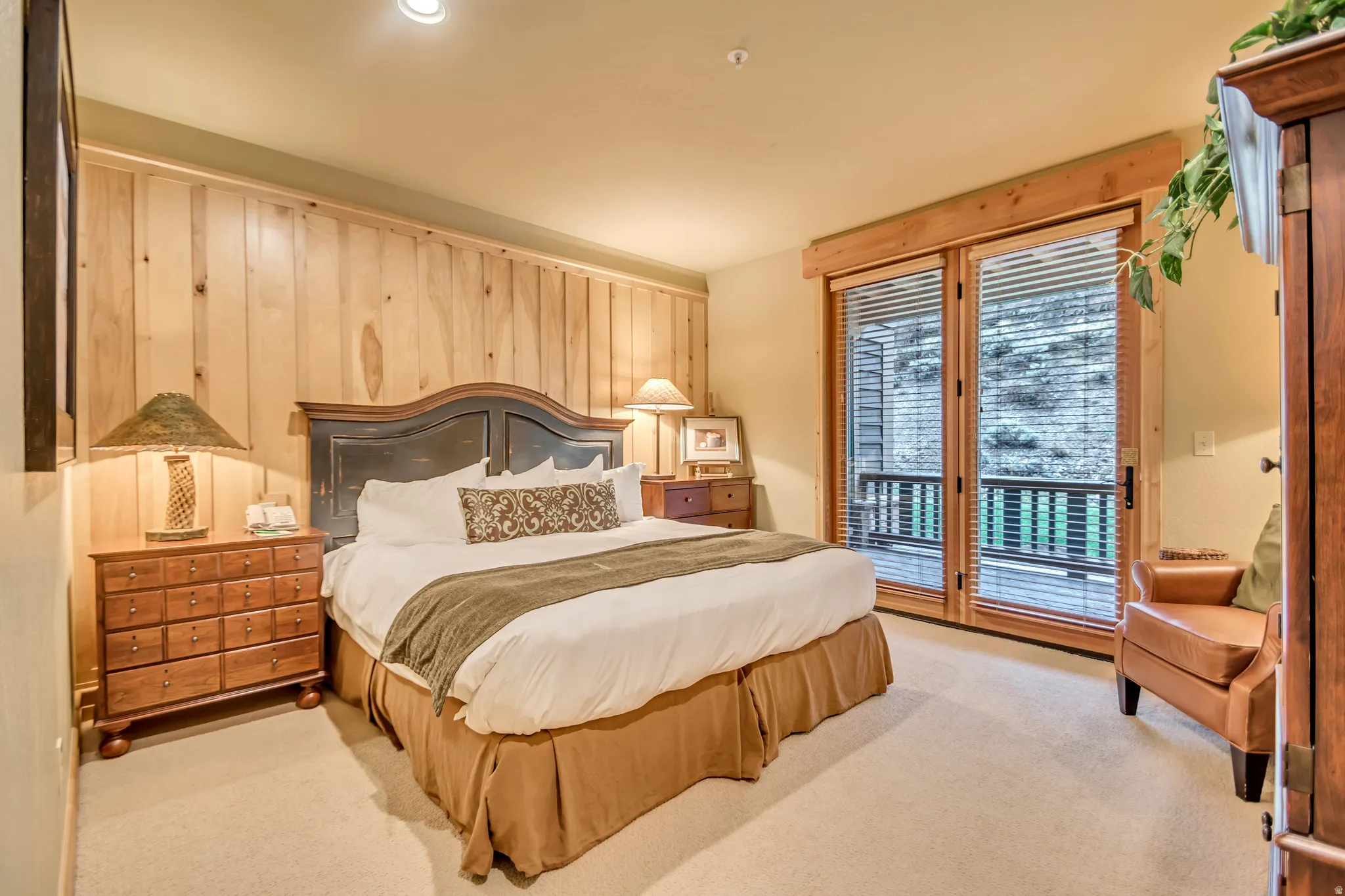 Bedroom featuring a wood-paneled accent wall, neutral-toned carpet, and recessed lighting