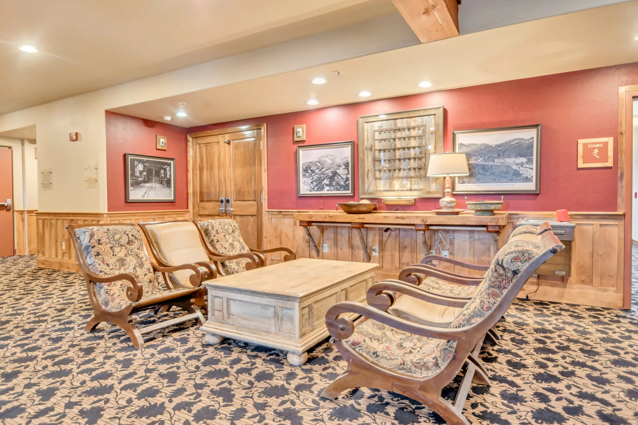 Lounge area featuring patterned carpet flooring, recessed lighting, and a wood beam ceiling accent