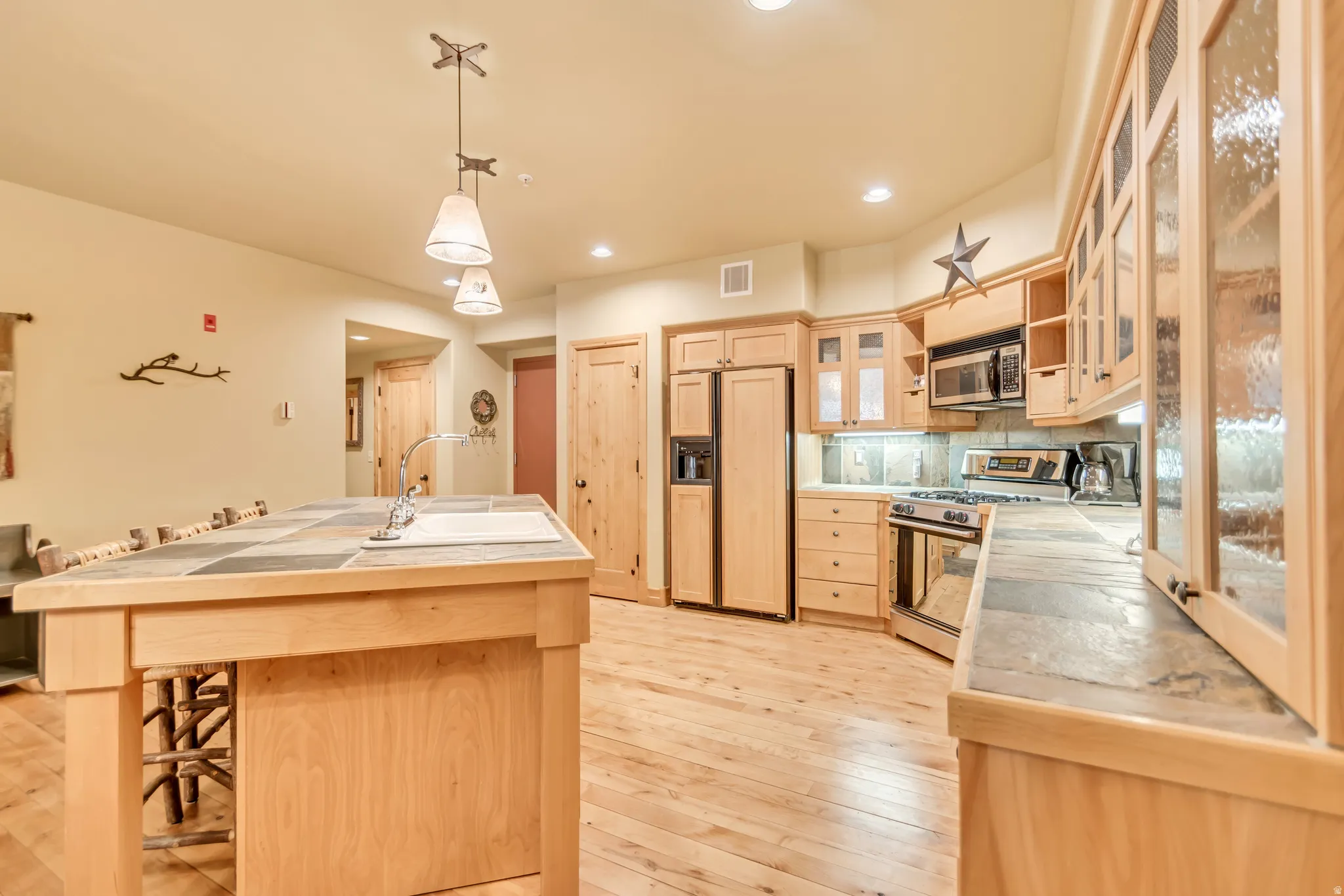 Kitchen featuring light wood cabinetry, stainless steel appliances, and wood-finish flooring