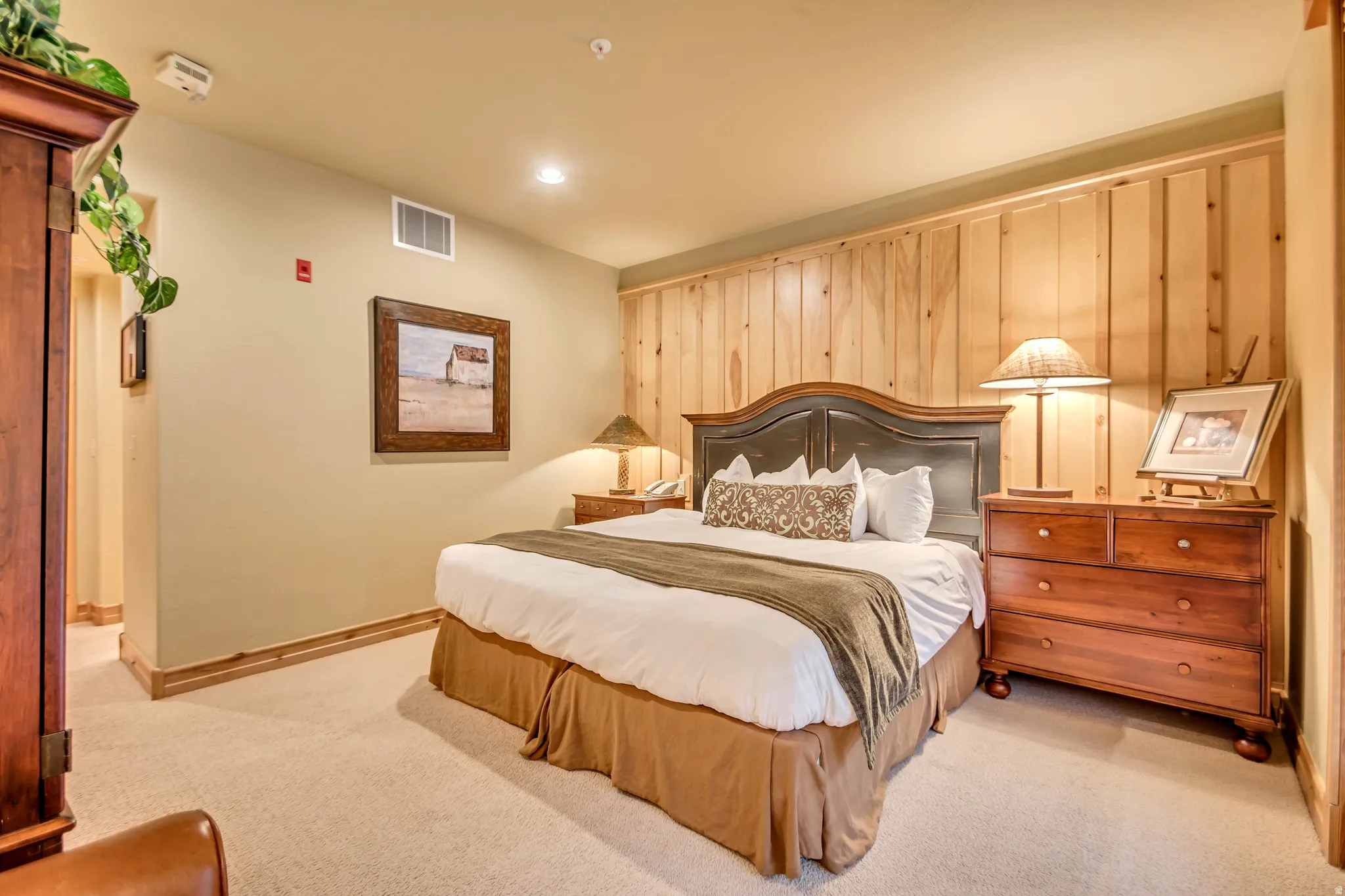 Carpeted bedroom with wood paneling accent wall, recessed lighting, and crown molding