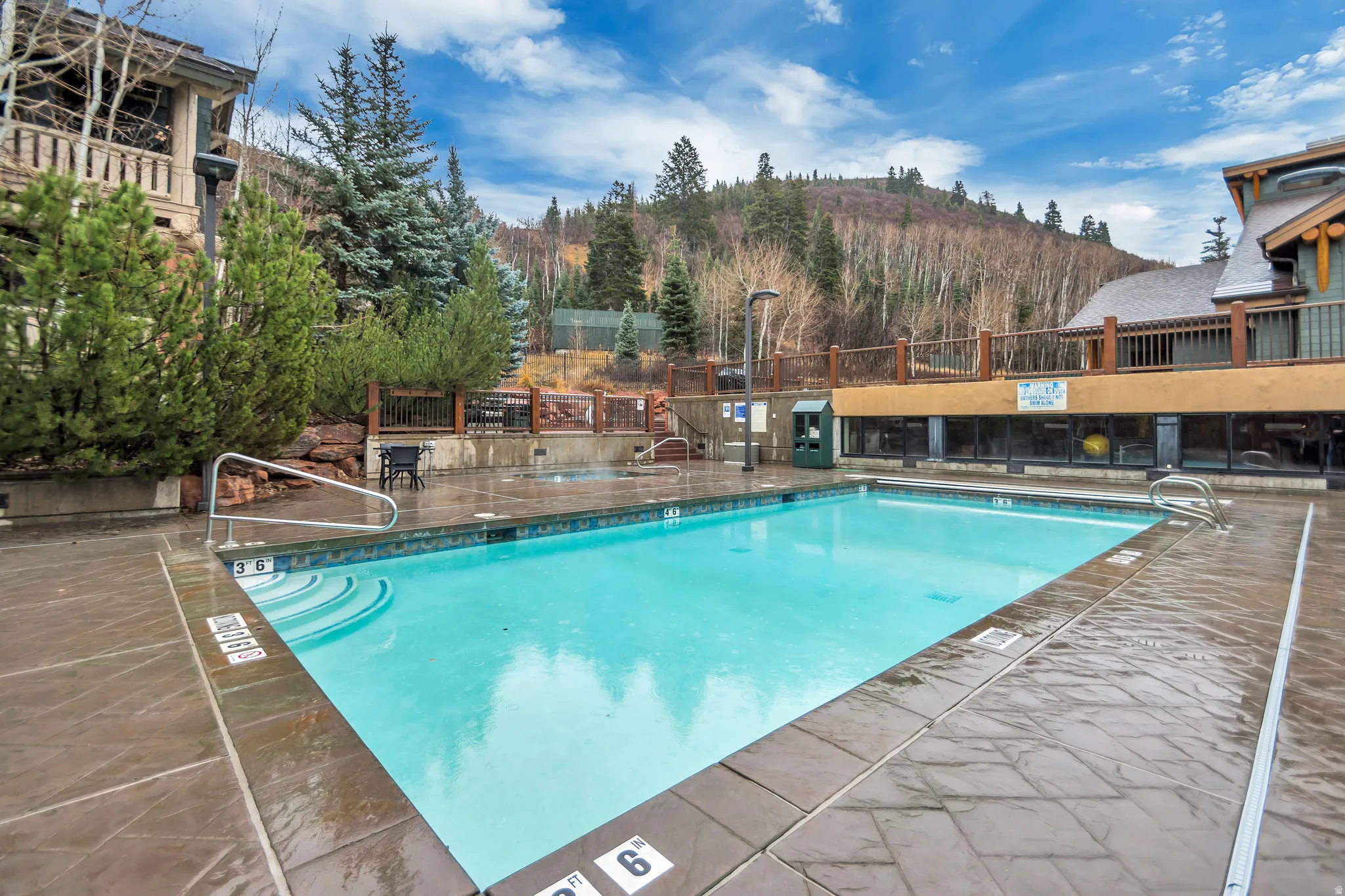 Outdoor swimming pool with integrated steps, surrounded by stone-finish decking