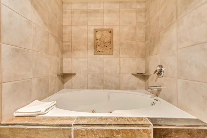 White jetted soaking tub with a tiled surround