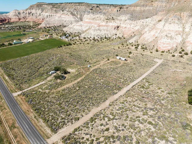 Expansive undeveloped land featuring a paved road frontage, established dirt access roads, and diverse natural vegetation