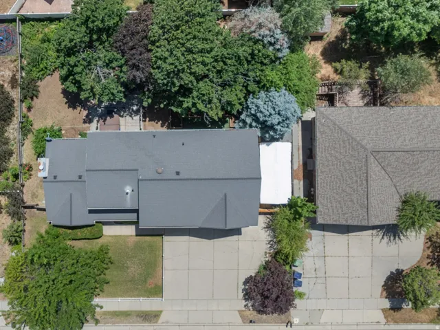 Expansive property featuring a large gray-roofed residence, a significant paved driveway, and mature landscaping