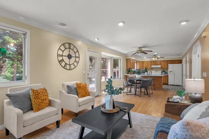Open-concept living space featuring wood-finish flooring, recessed lighting, and crown molding