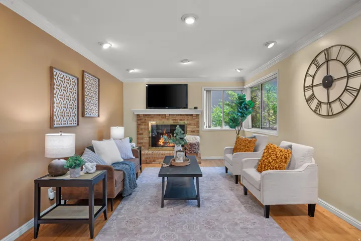 Living area featuring a brick fireplace with a white mantel, recessed lighting, and crown molding