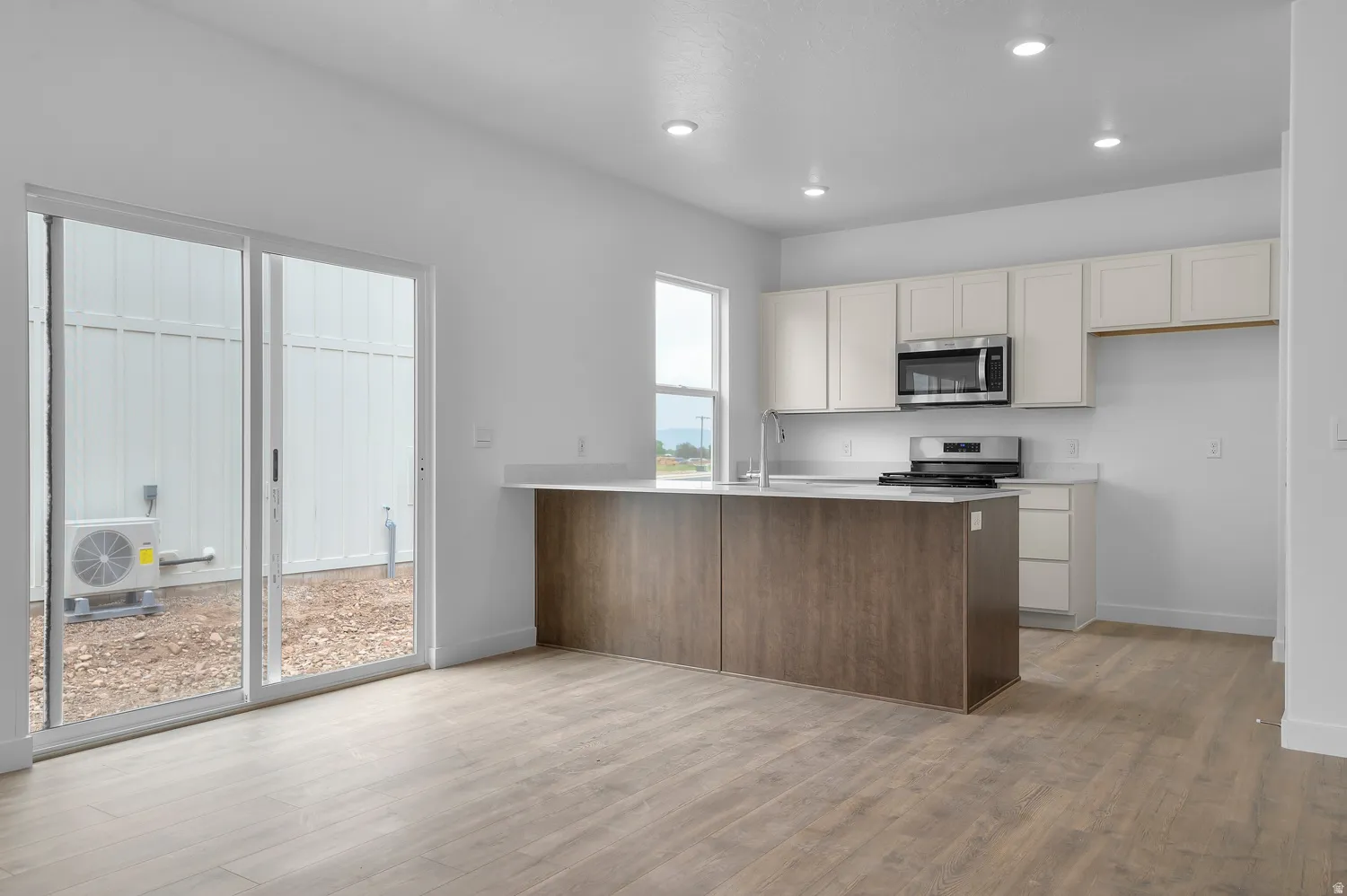 Open-concept kitchen with white cabinetry and an integrated island featuring a wood-finish base