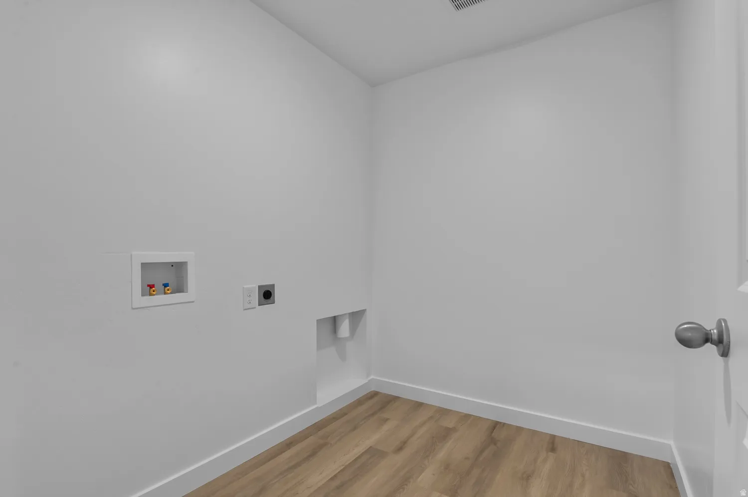 Dedicated utility space featuring light wood-finish flooring and white baseboards