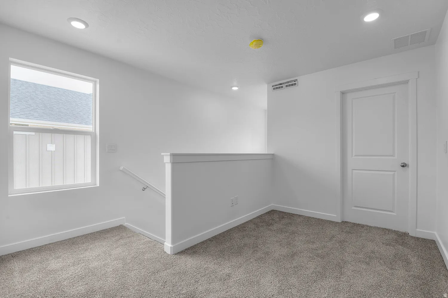 Upper-level landing featuring plush gray carpet, a white framed window, and recessed lighting
