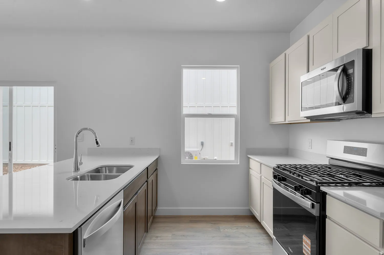 Modern kitchen featuring light wood-finish flooring, white countertops, and a gas range