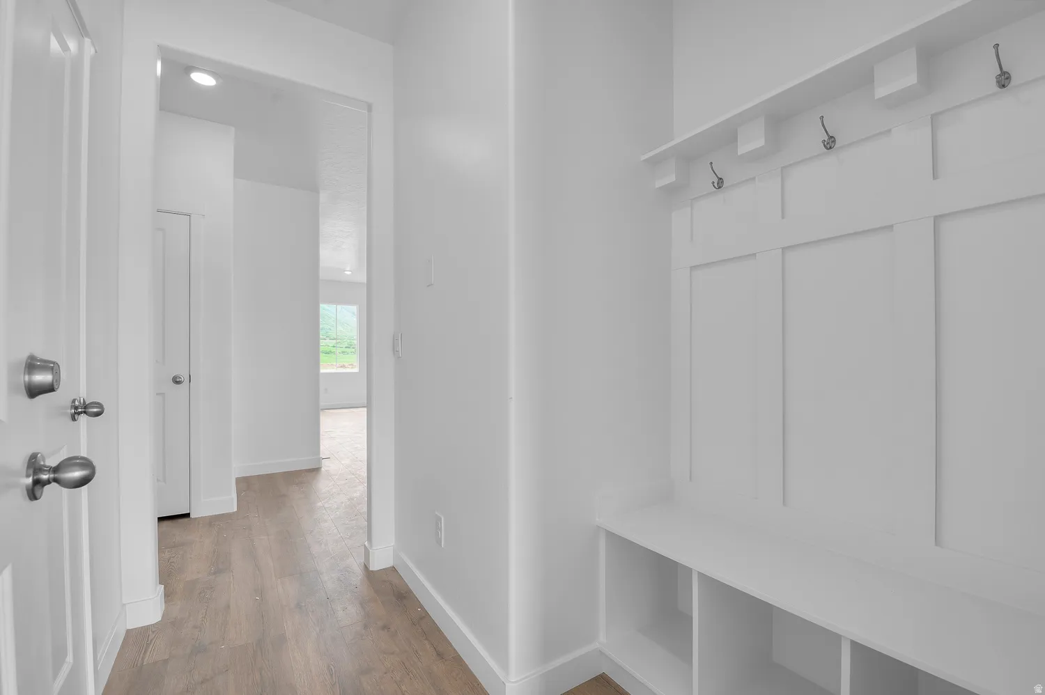 Entryway featuring a built-in bench with storage cubbies and coat hooks, alongside wood-finish flooring