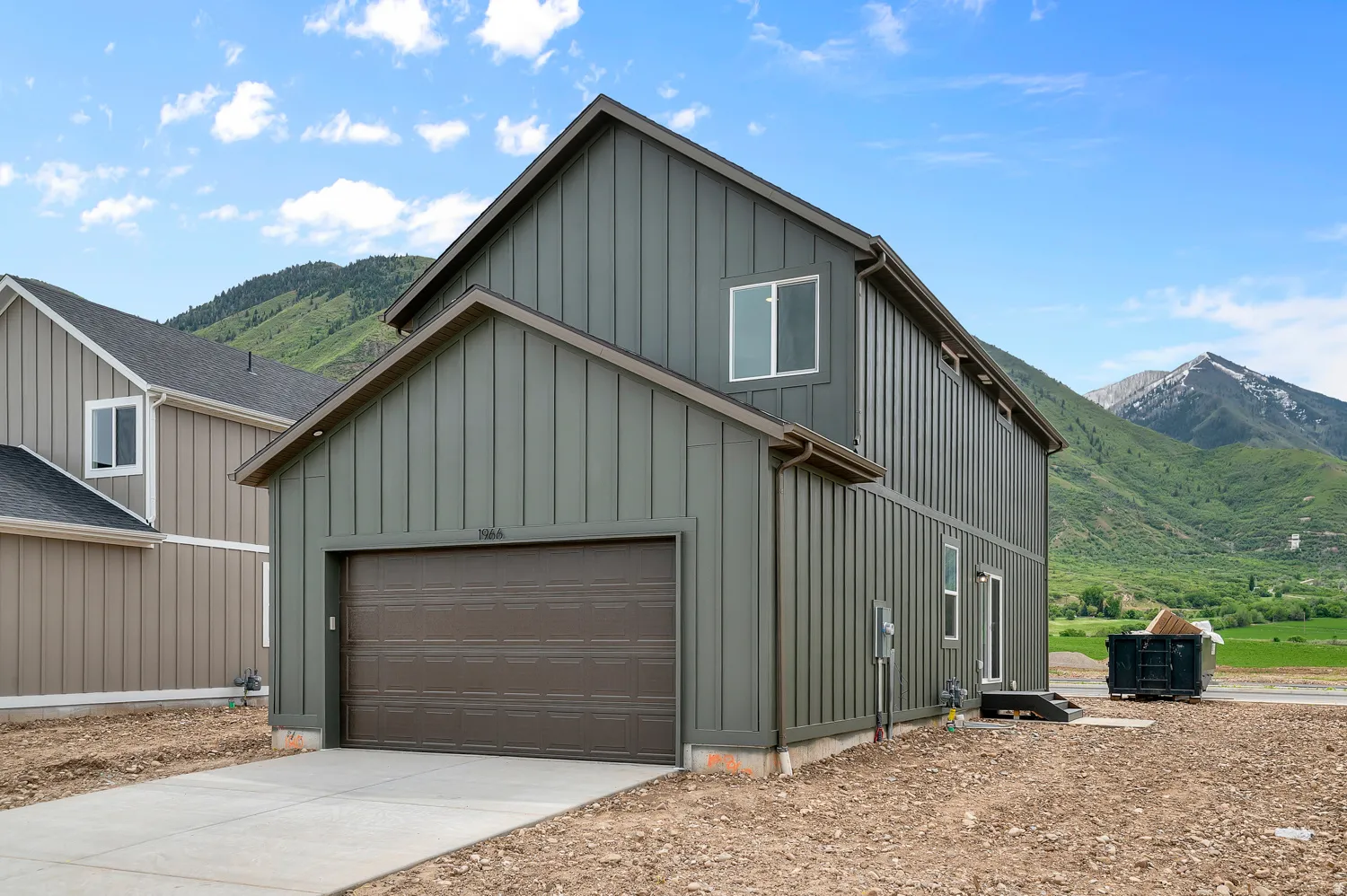 Board and batten siding with a neutral tone, brown garage door, and light-colored trim