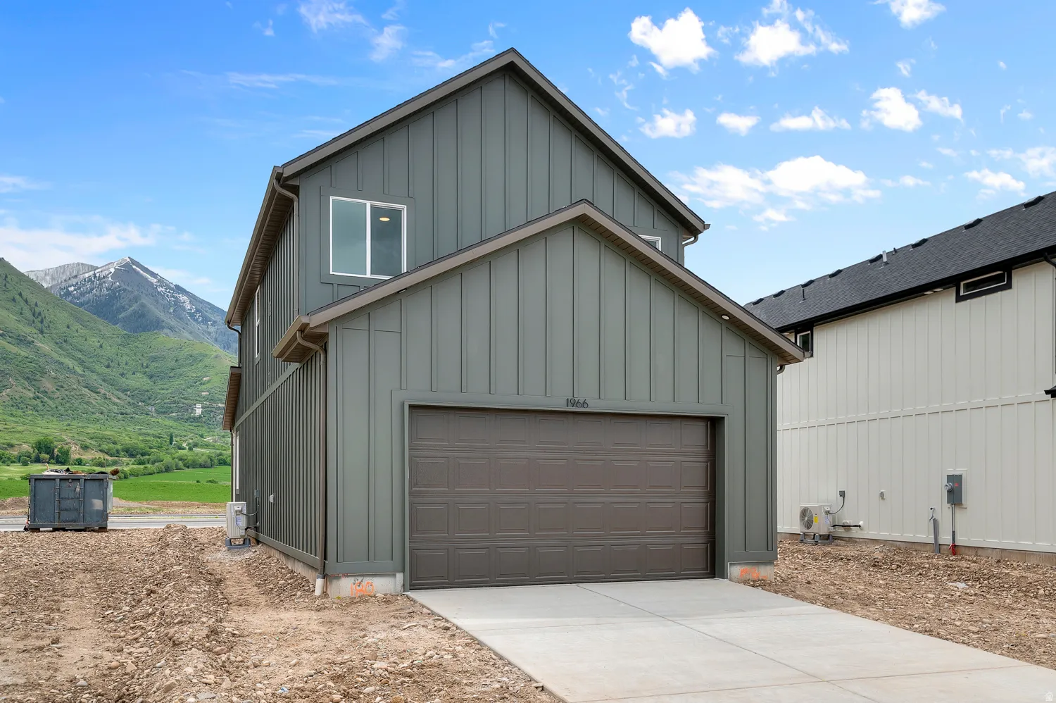 Two-story residence featuring contemporary vertical panel siding in a deep green hue and a brown garage door