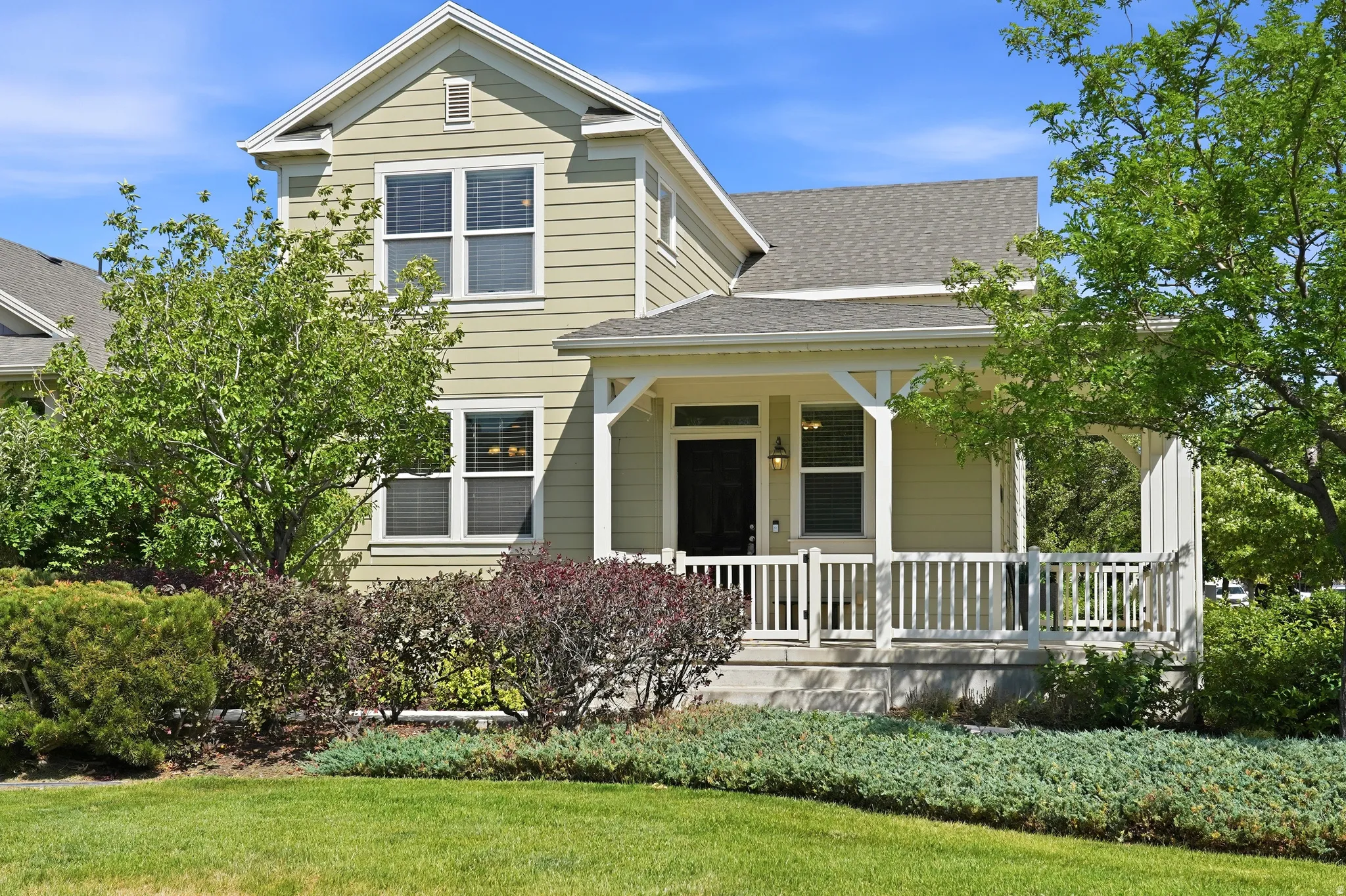 Two-story residence featuring light green siding and a covered front porch with white railings