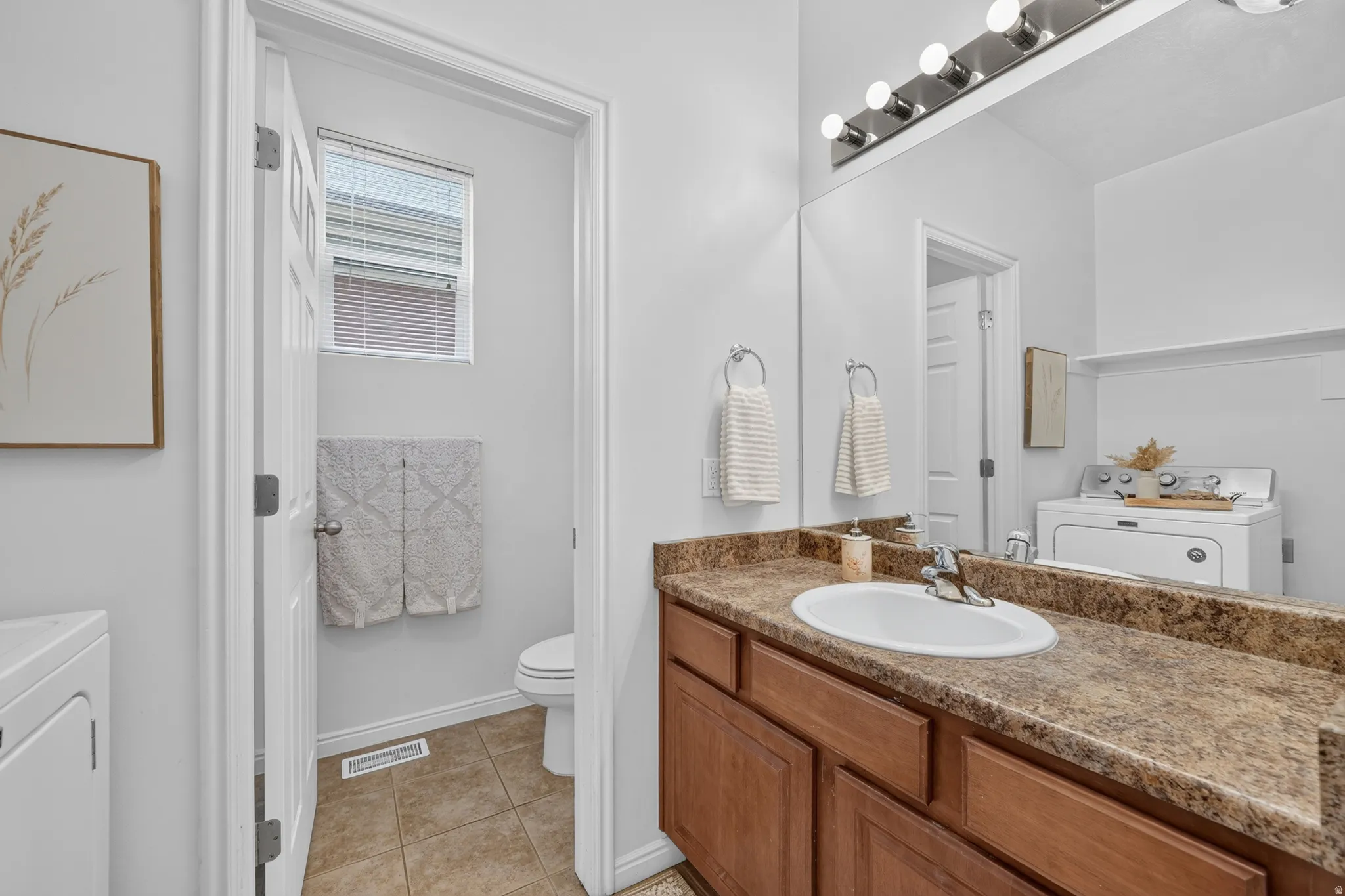 Bathroom vanity featuring a single basin sink, brown wood cabinetry, and a patterned countertop