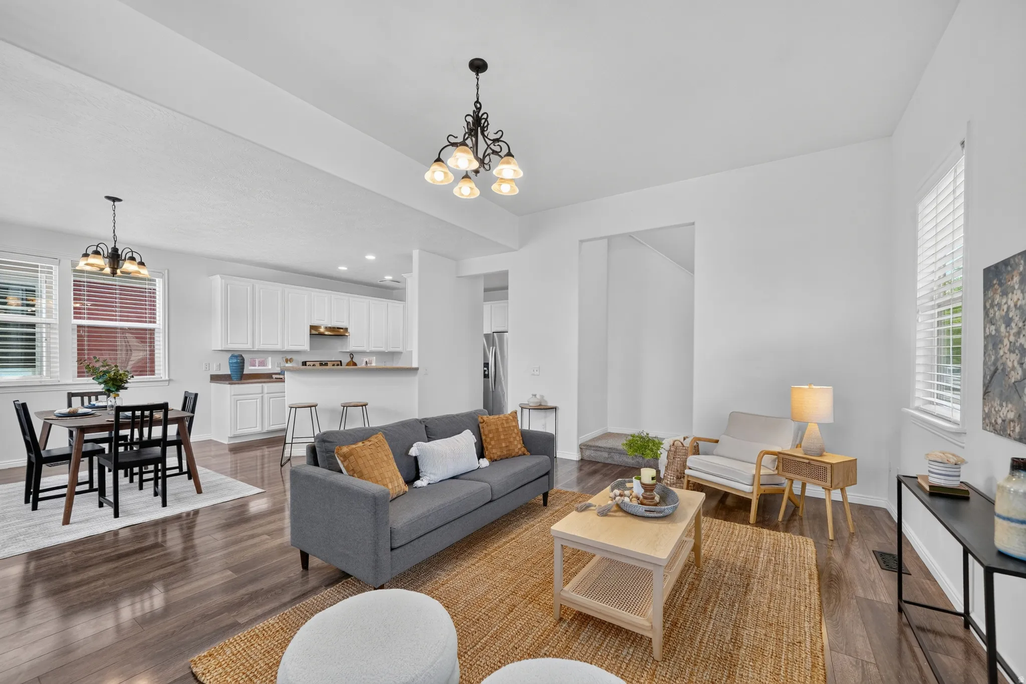 Open-concept living area featuring dark wood-finish flooring, white walls, and recessed lighting