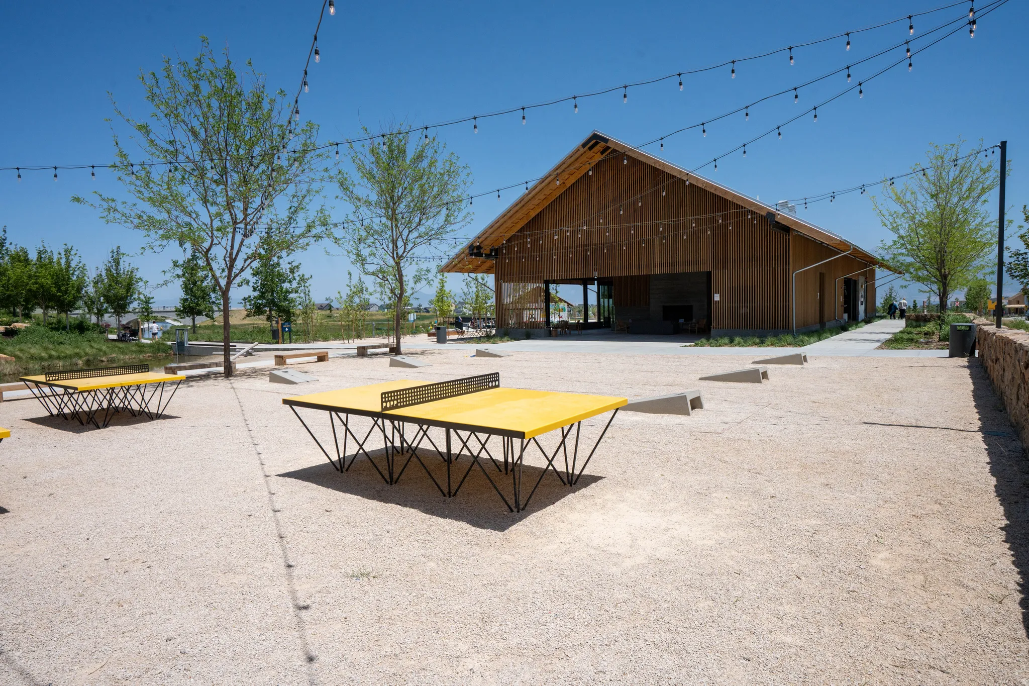 Expansive outdoor area featuring a gravel surface, string lighting, and mature trees