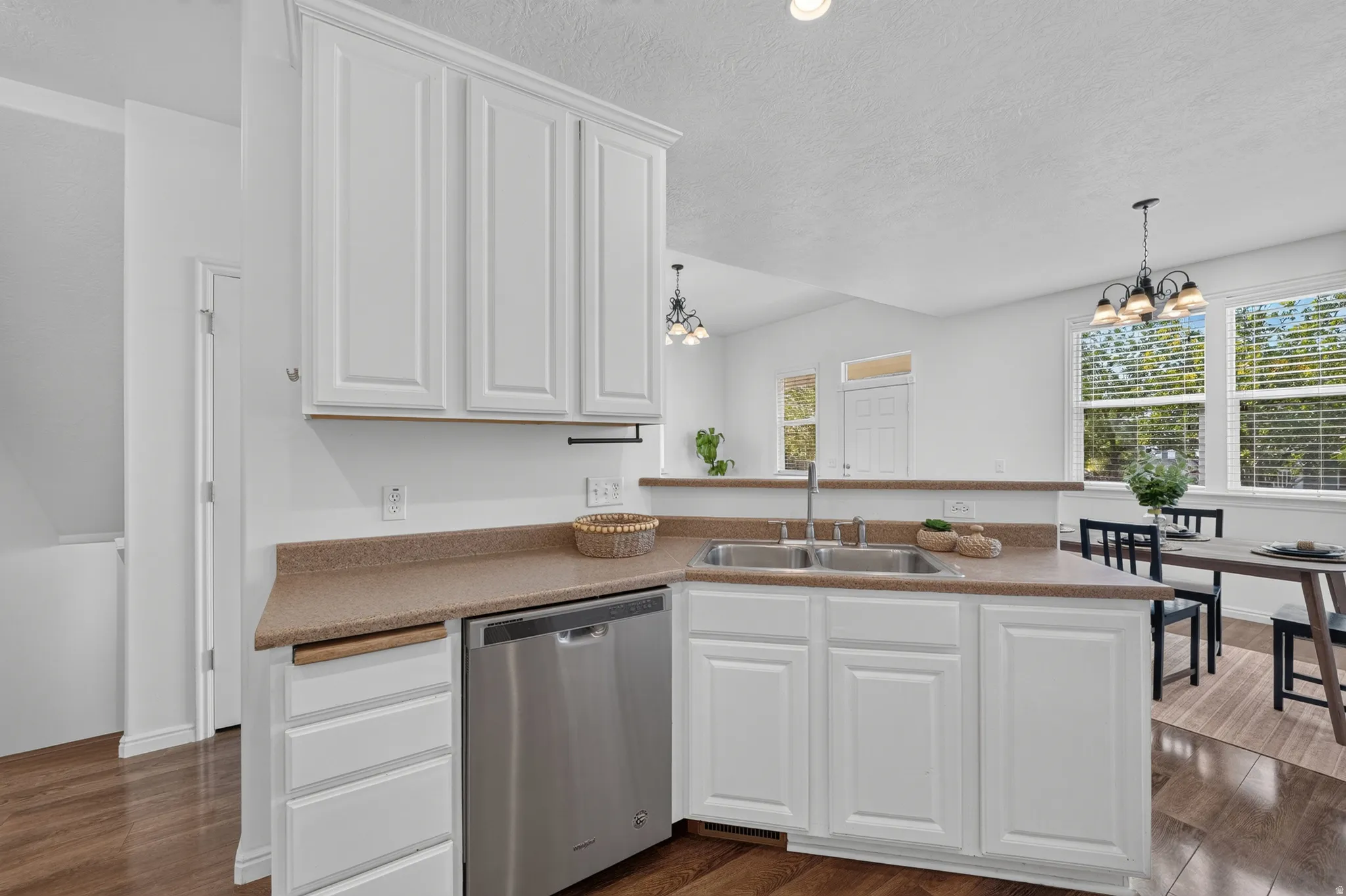 Modern kitchen featuring white shaker cabinetry, stainless steel dishwasher, double basin sink, and wood-finish flooring