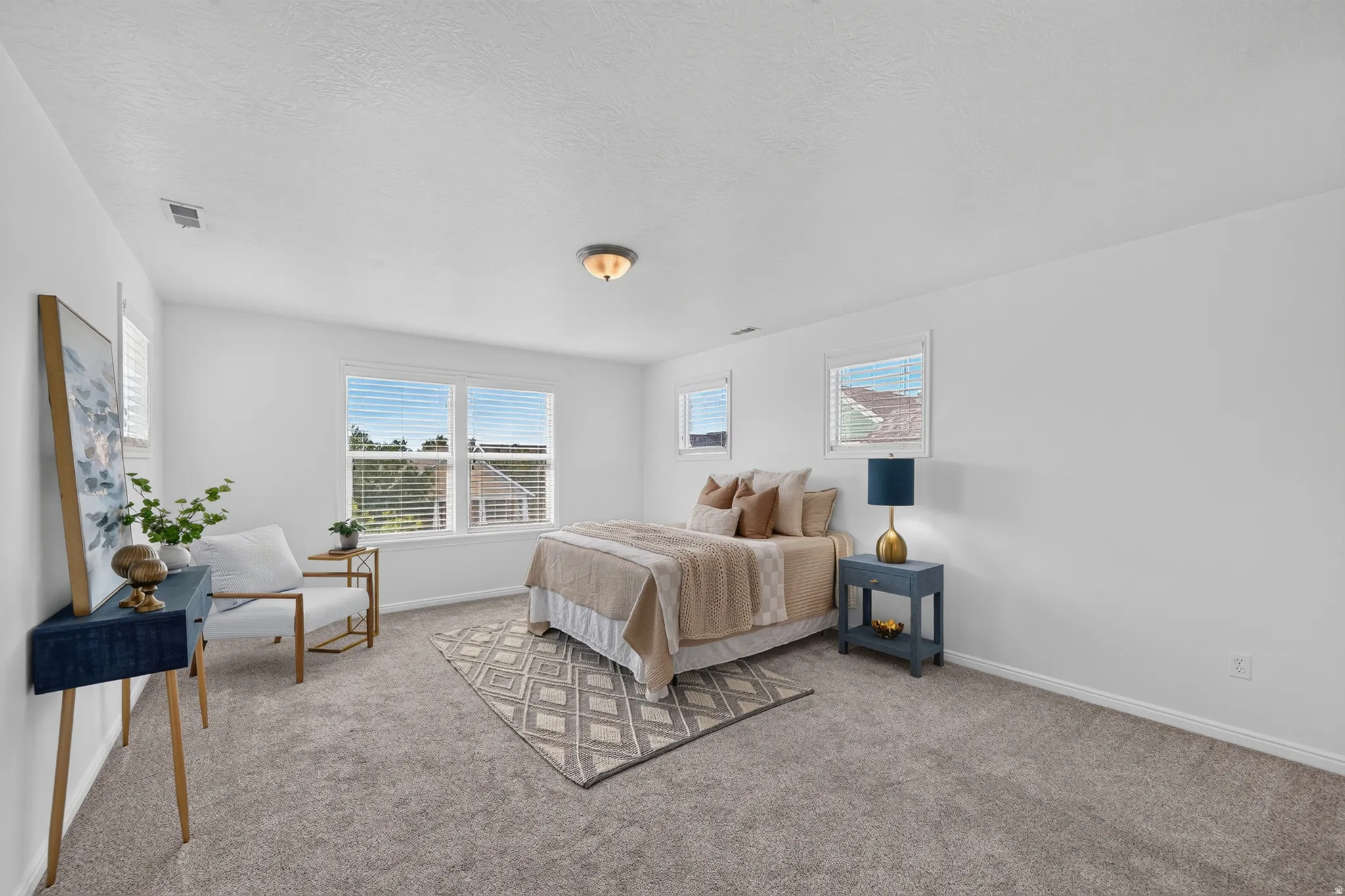 Carpeted bedroom featuring white walls, multiple windows with blinds, and a flush mount ceiling light