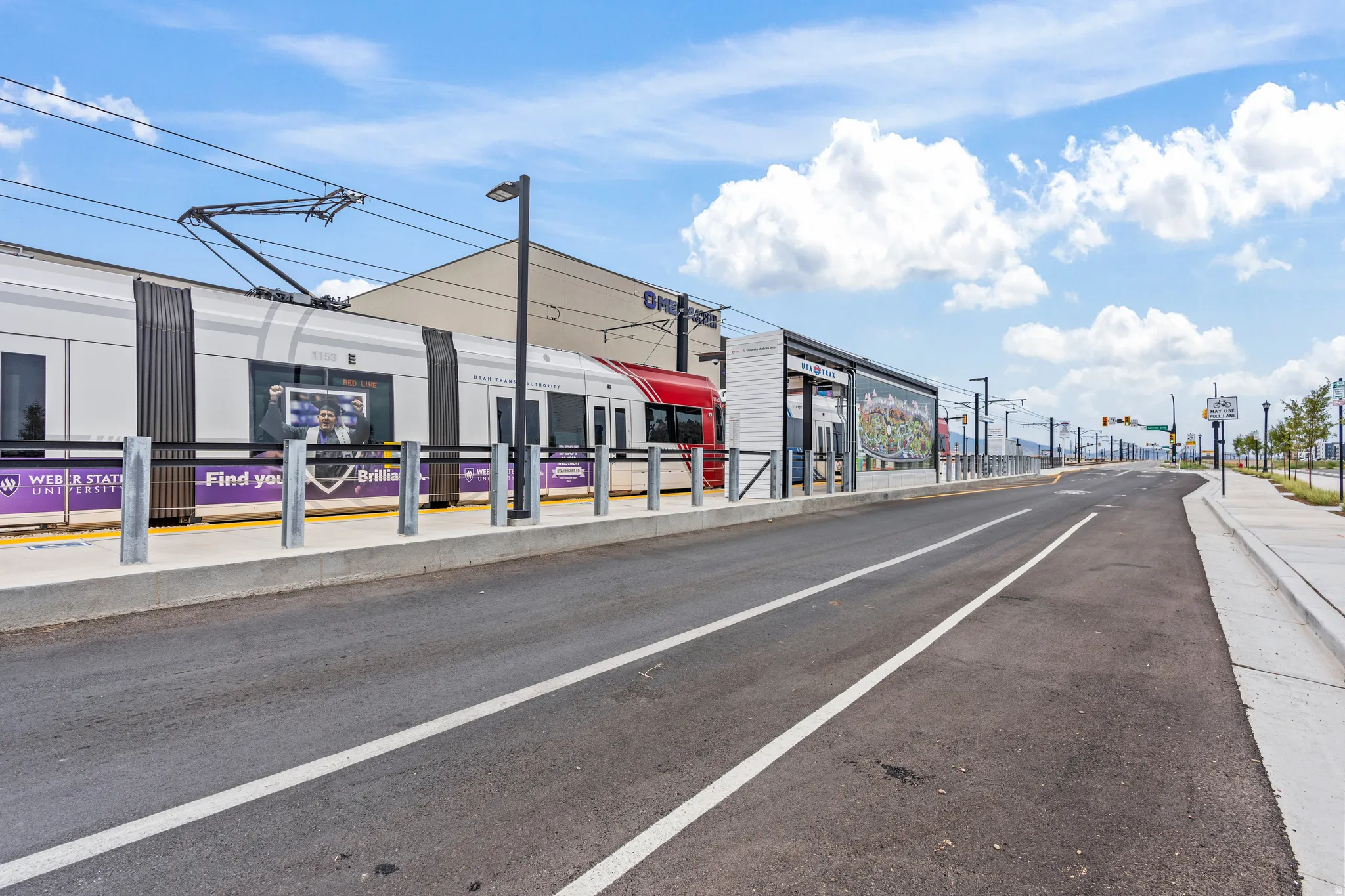 Modern transportation infrastructure featuring a light rail station, paved road, and concrete sidewalks