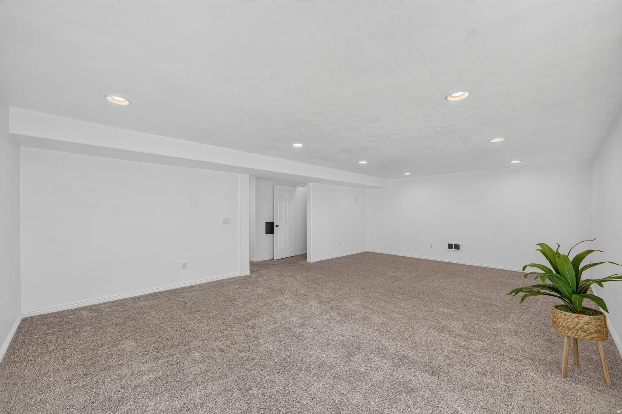 Spacious room featuring neutral carpeting and white walls