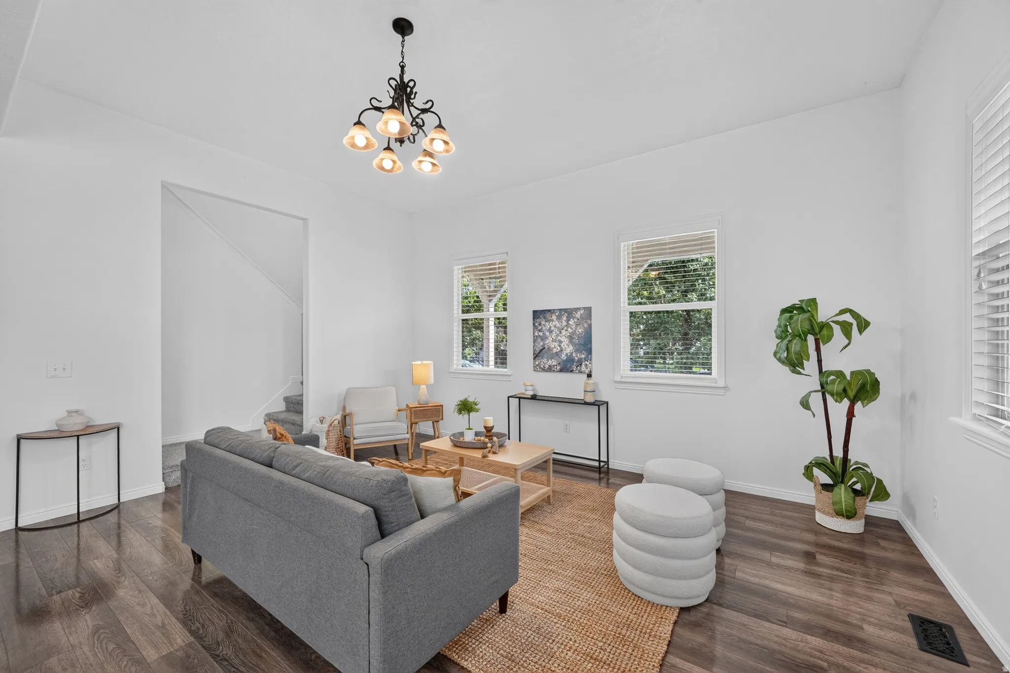 Spacious living area featuring wood-finish flooring, bright white walls, and multiple windows