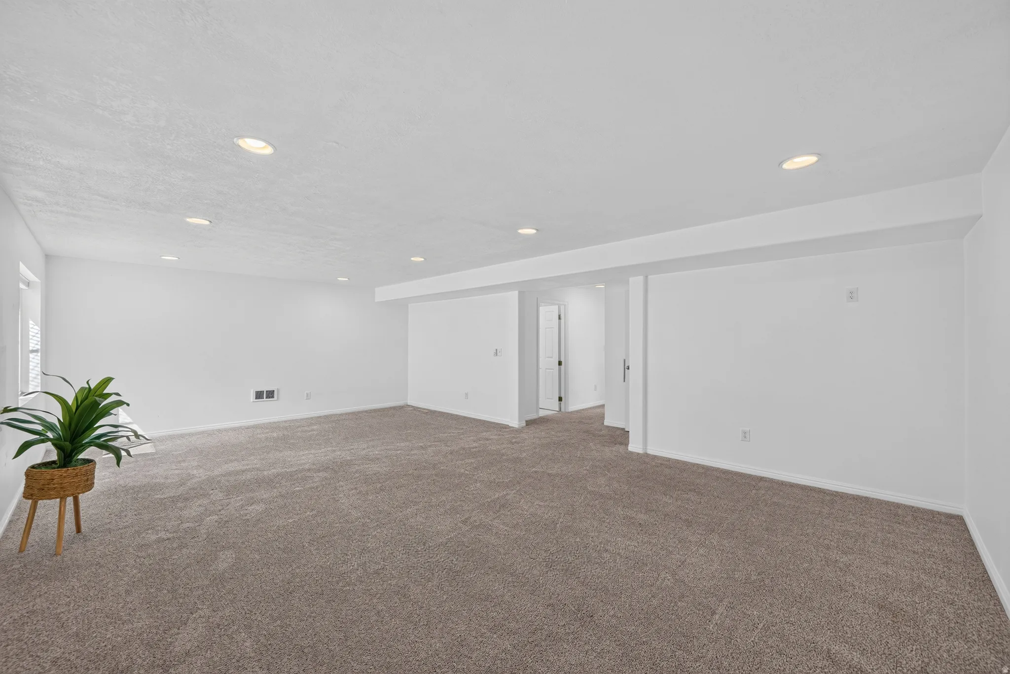 Spacious room with plush carpet flooring, recessed lighting, and bright white walls