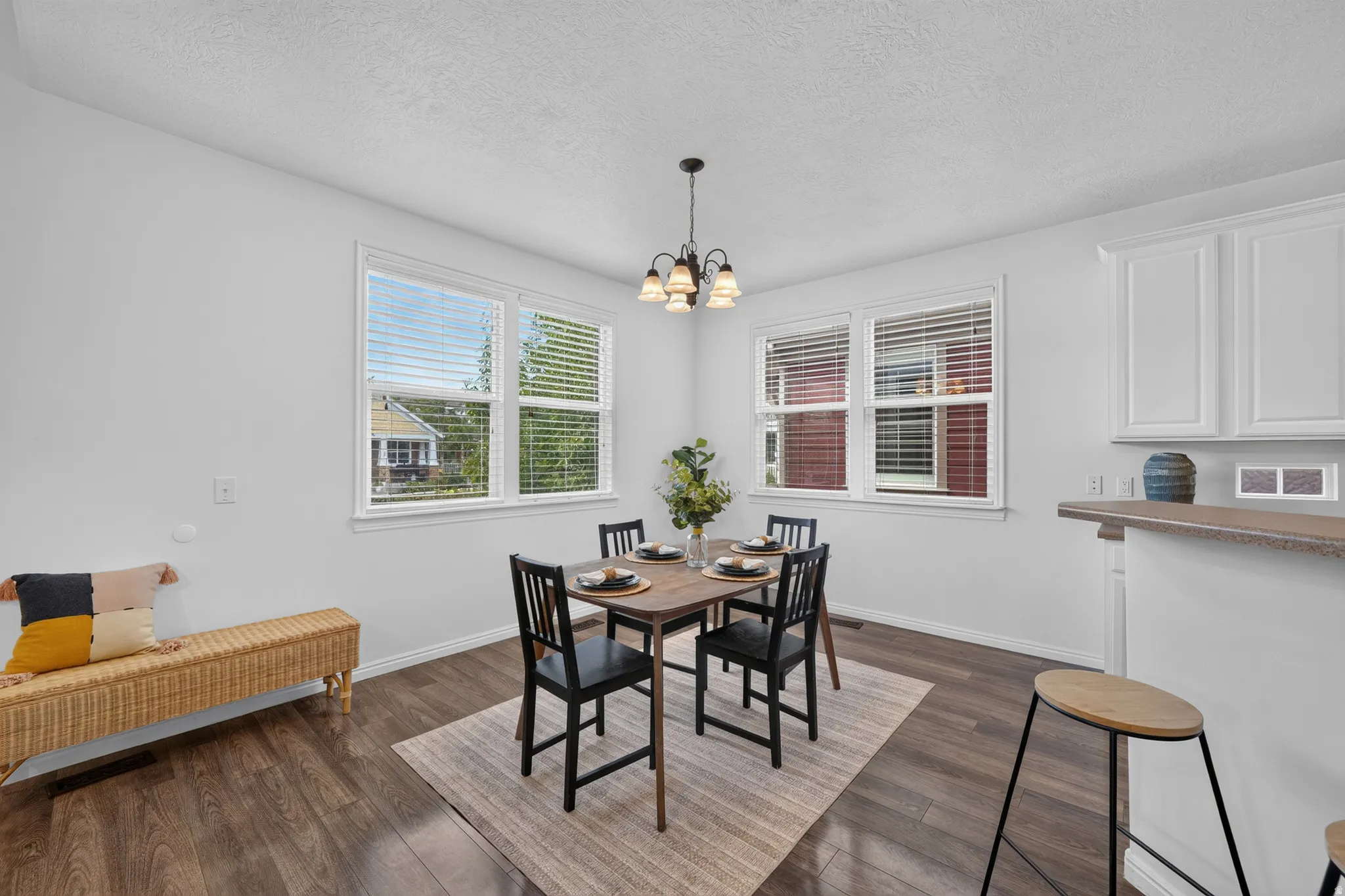 Dining area featuring wood-finish flooring, white baseboards, and a contemporary chandelier