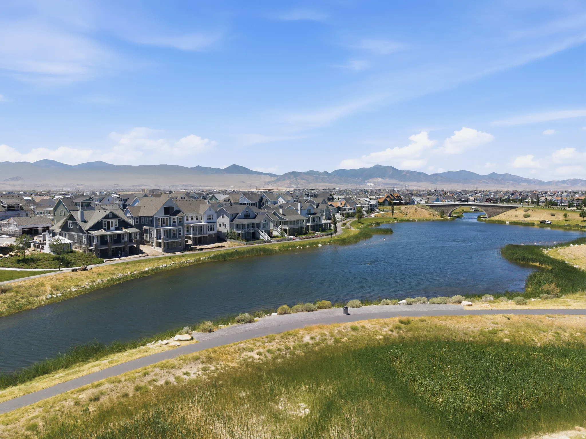 Lakeside community featuring a paved walking path, surrounding wetlands, and distant mountain ranges
