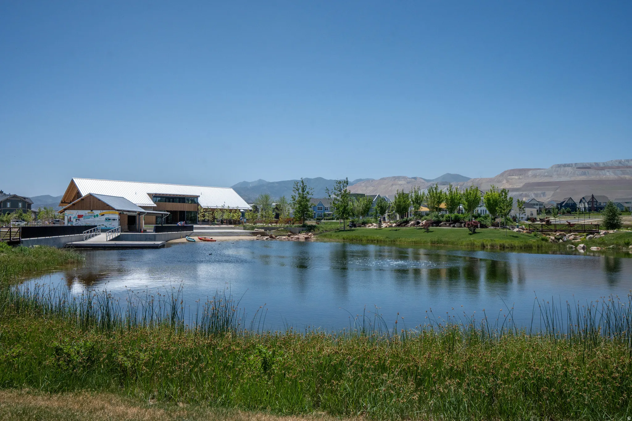 Community lake featuring a modern boathouse with a metal roof and a wooden facade