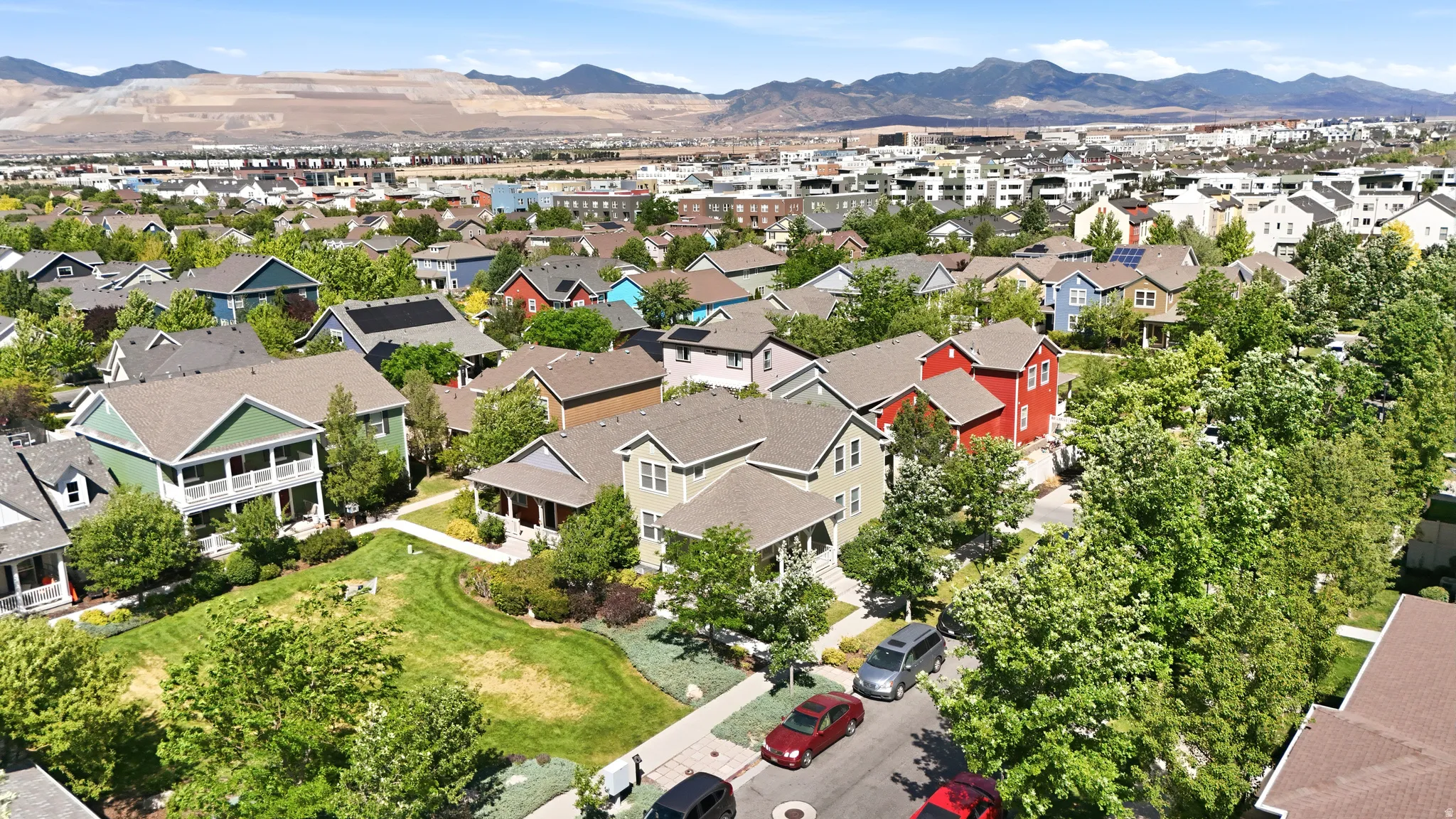 Aerial perspective of a developed residential area featuring various architectural styles, mature trees, and a distant mountain range