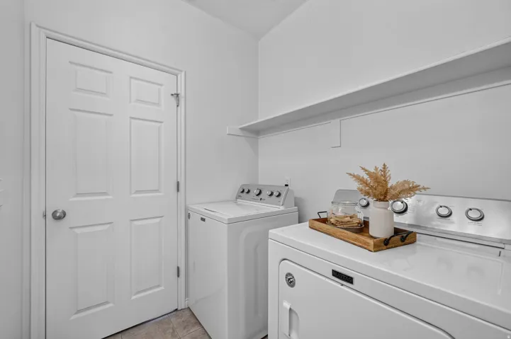 Dedicated laundry area featuring a white six-panel door, built-in wall shelving, and tile flooring