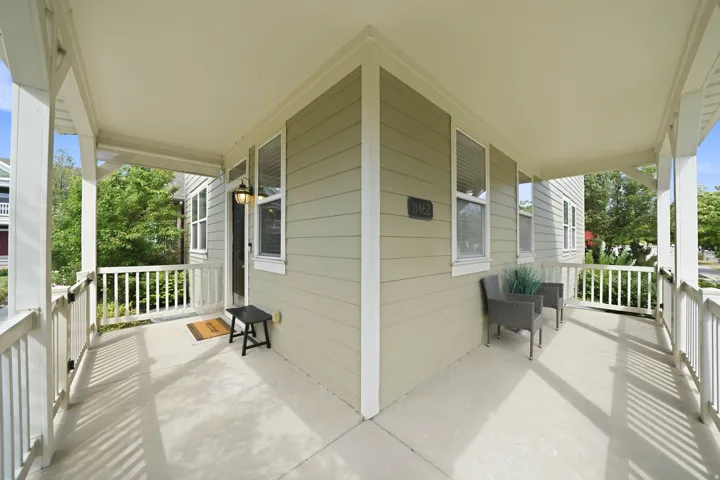 Expansive wrap-around porch featuring a light-colored concrete surface, white railing, and a light green exterior with white trim
