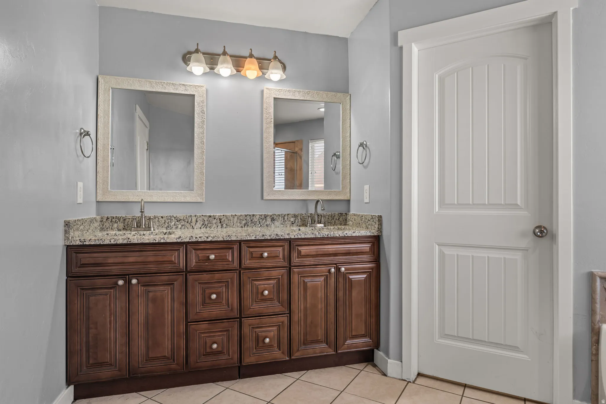 Dual vanity featuring a granite-style countertop, undermount sinks, and dark wood-finish cabinetry