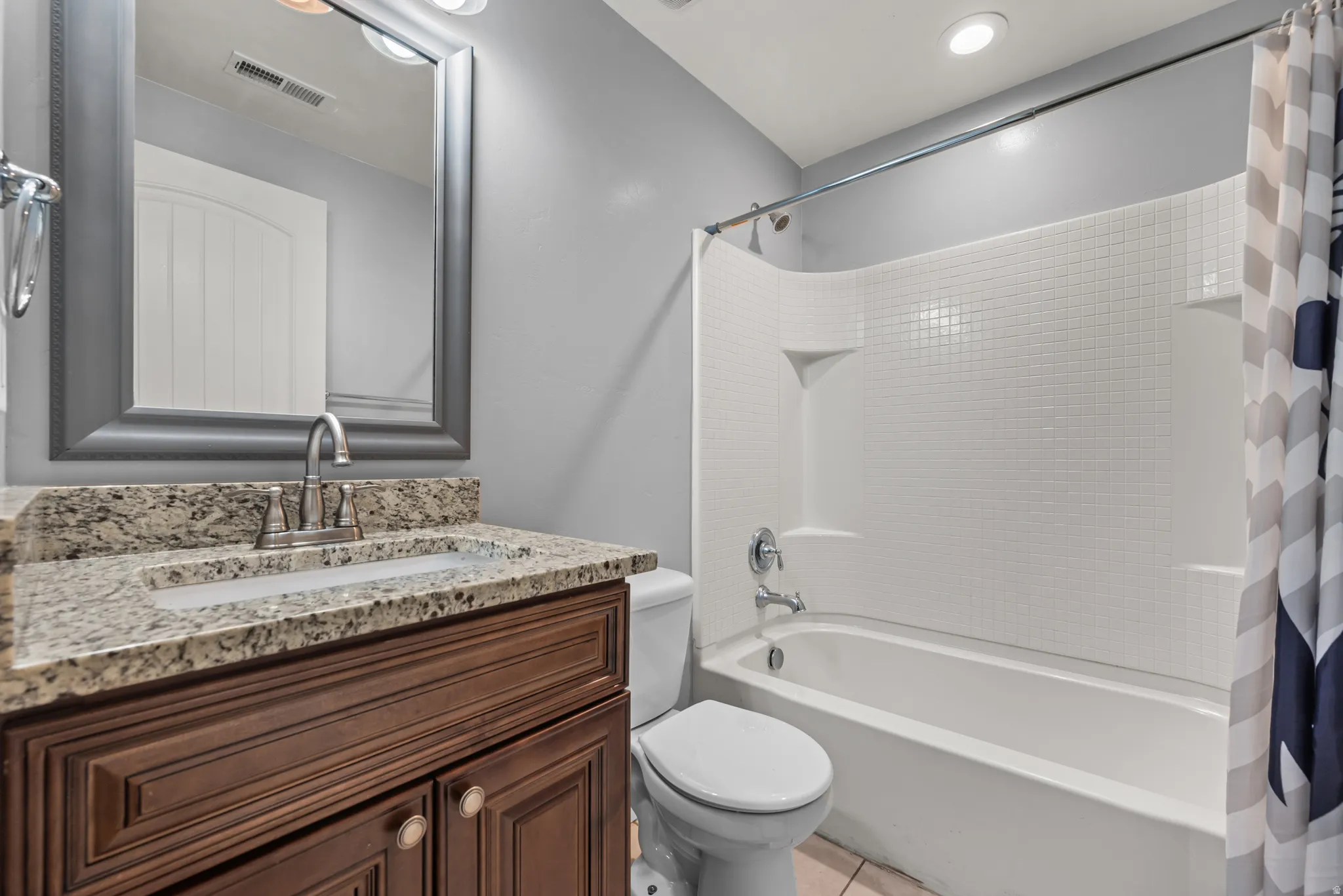 Bathroom featuring a wood-finish vanity with a granite countertop, undermount sink, and brushed nickel faucet