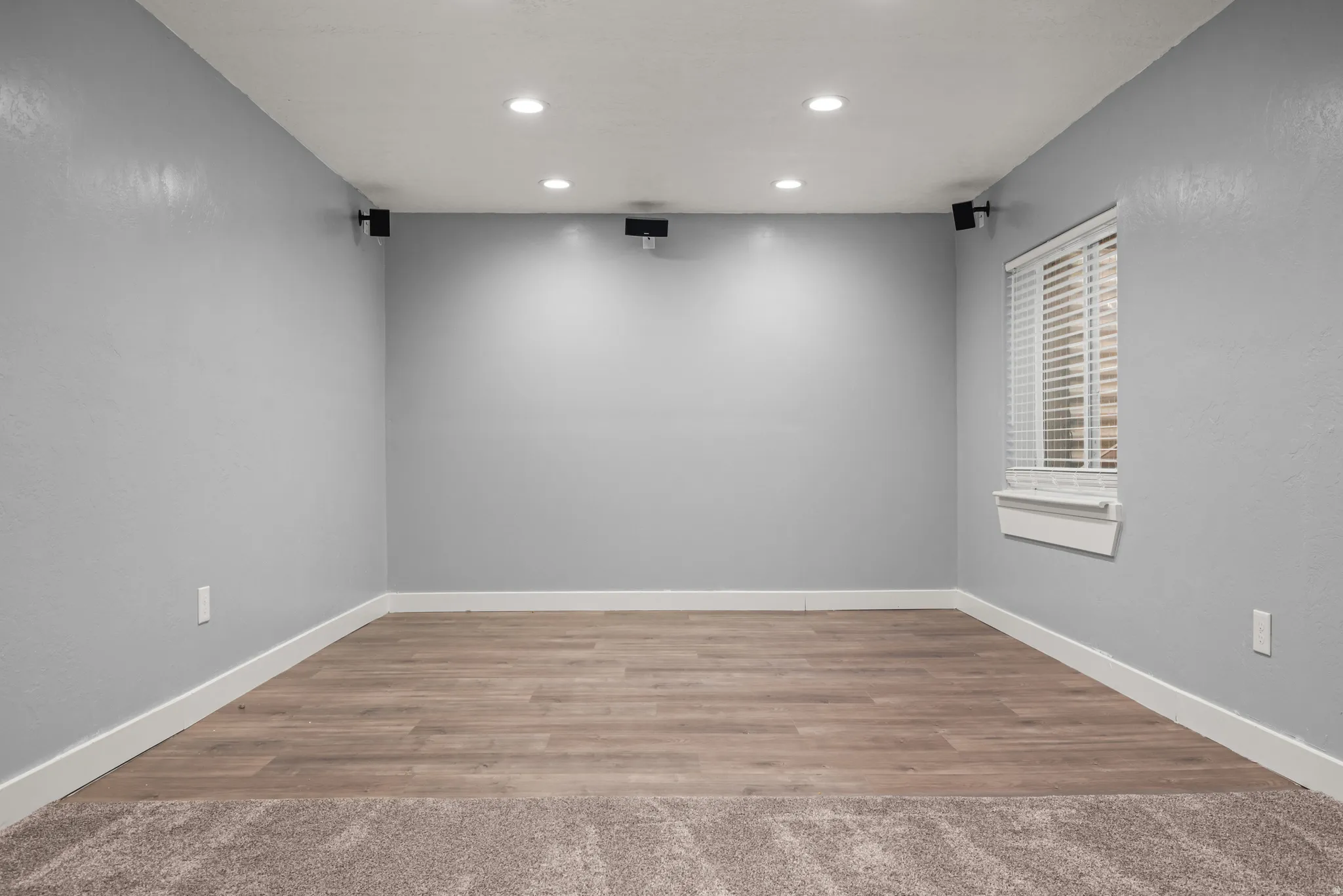 Versatile bonus room featuring recessed lighting, wall-mounted speakers, wood-finish flooring, and a window with blinds