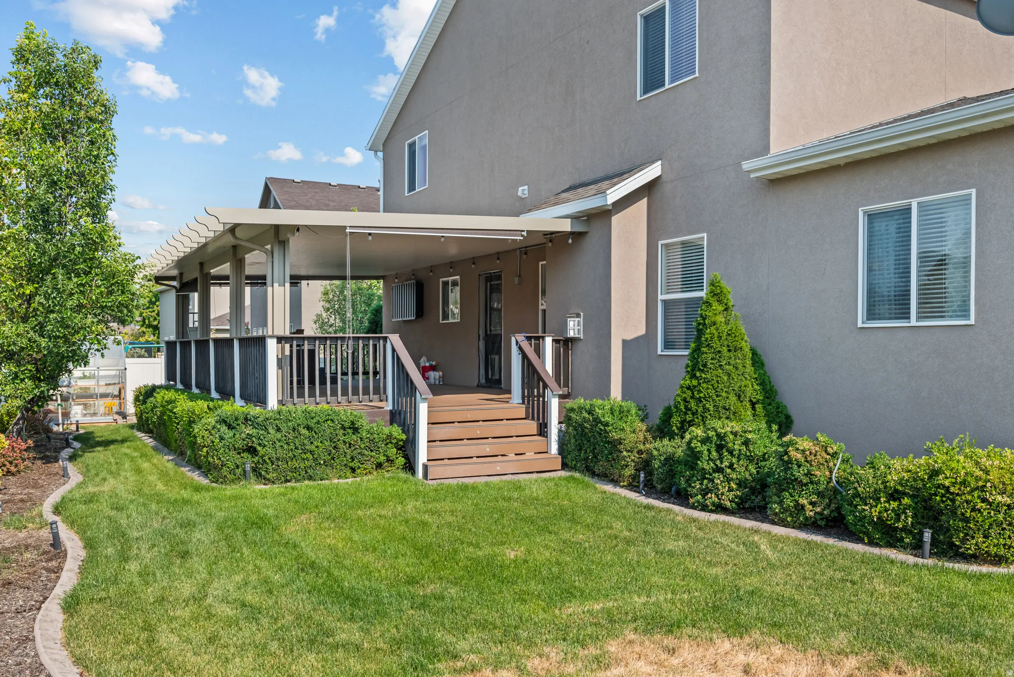 Expansive backyard featuring a covered patio, wood-finish decking, and built-in pergola