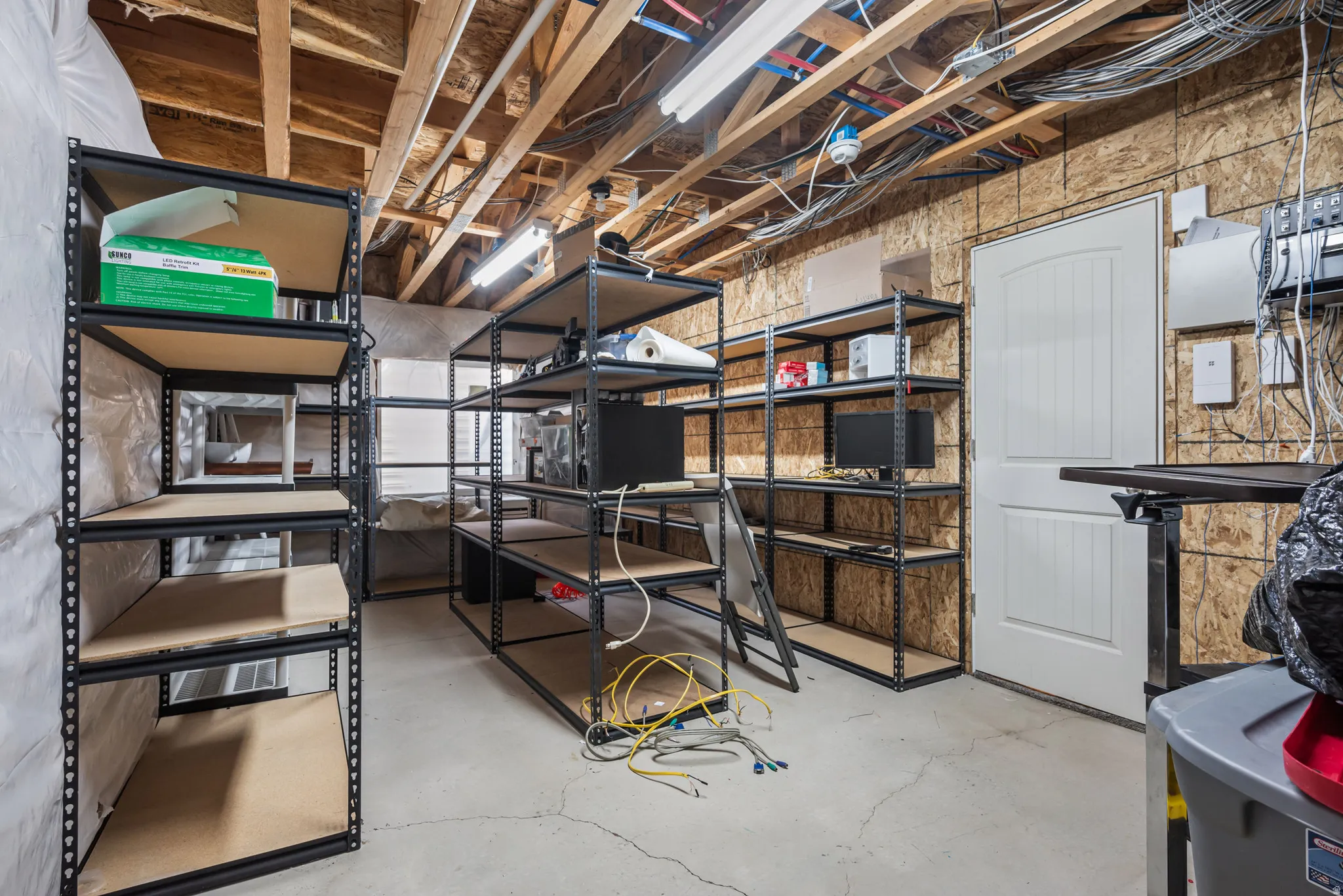 Utility area featuring exposed wood ceiling joists and concrete flooring