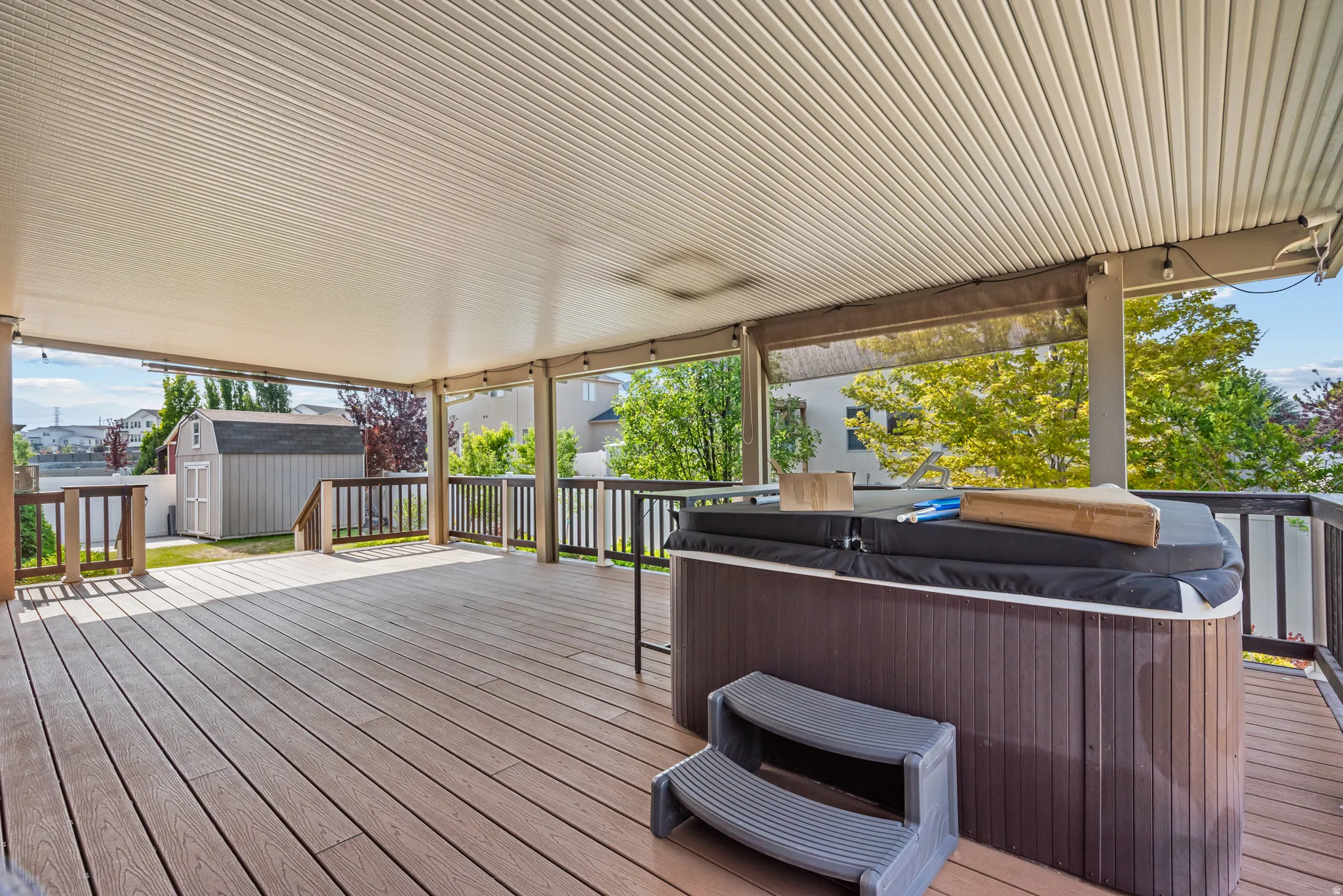 Expansive covered deck featuring wood-finish flooring and a built-in spa