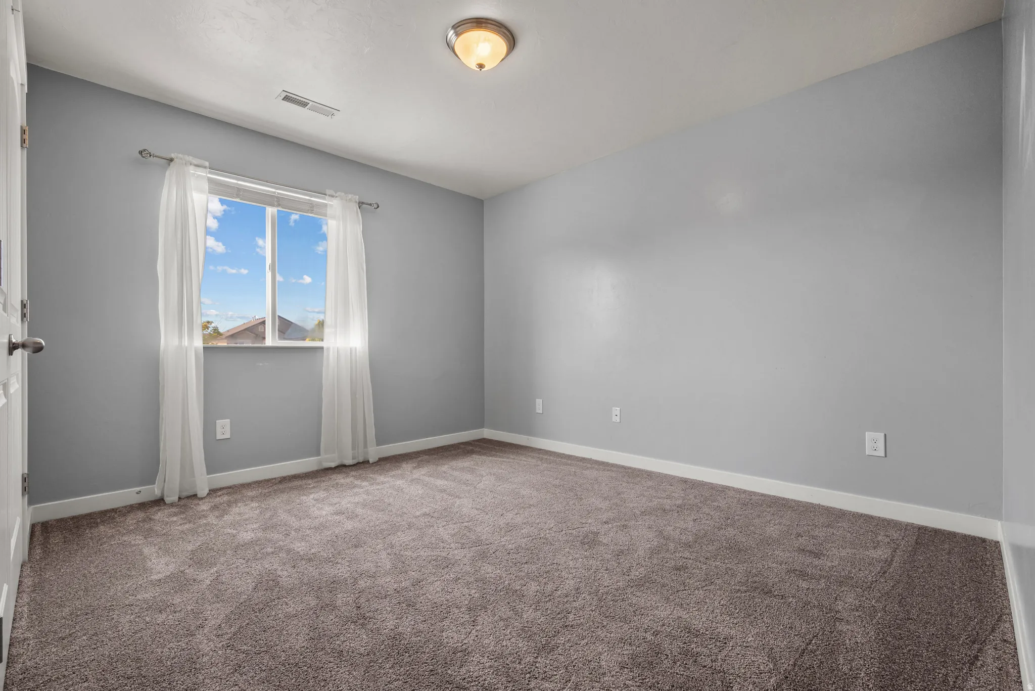 Window-equipped room featuring neutral gray walls and brown carpet flooring